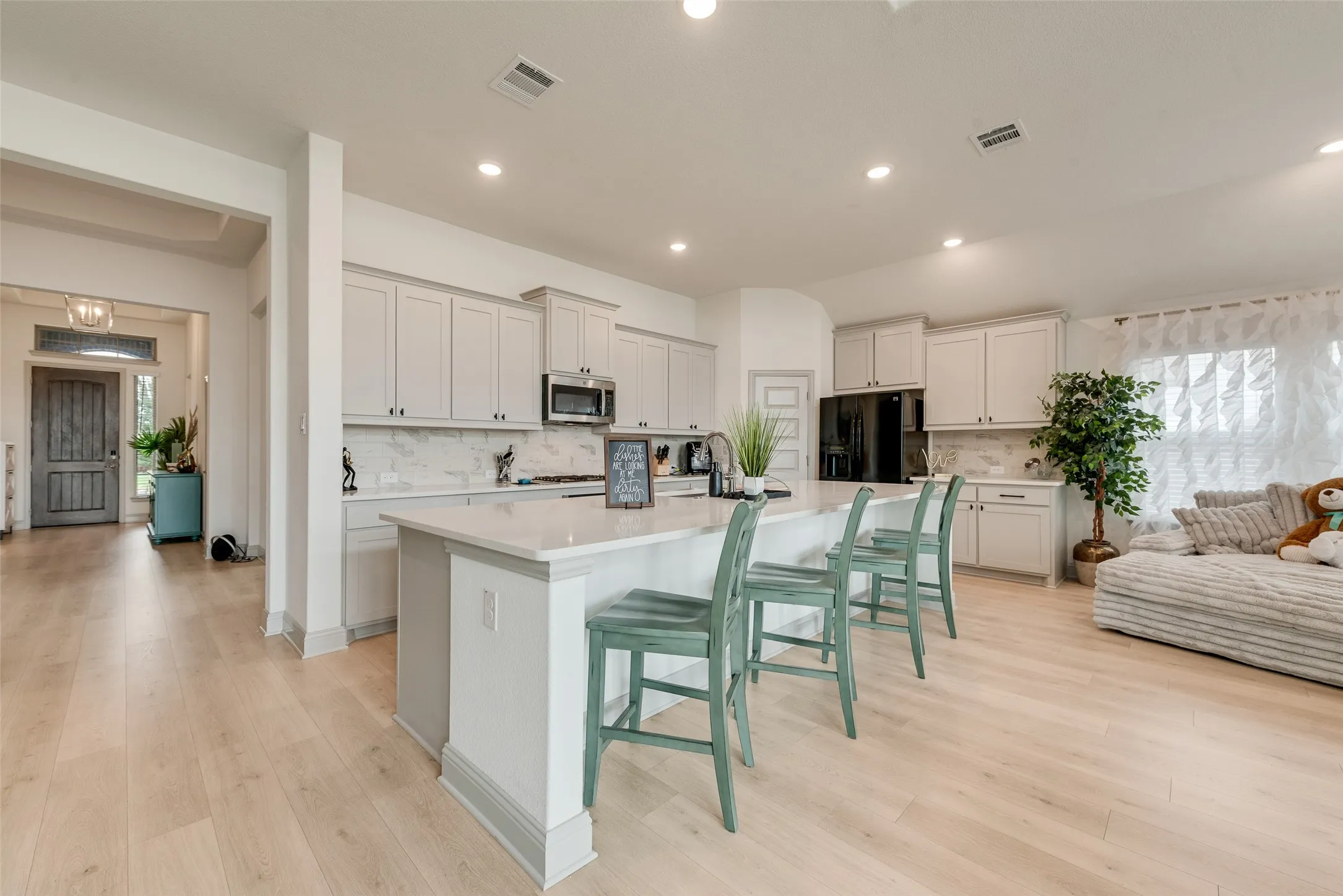 Kitchen featuring light-toned cabinetry, a central island with countertop seating, stainless steel appliances, and wood-finish flooring