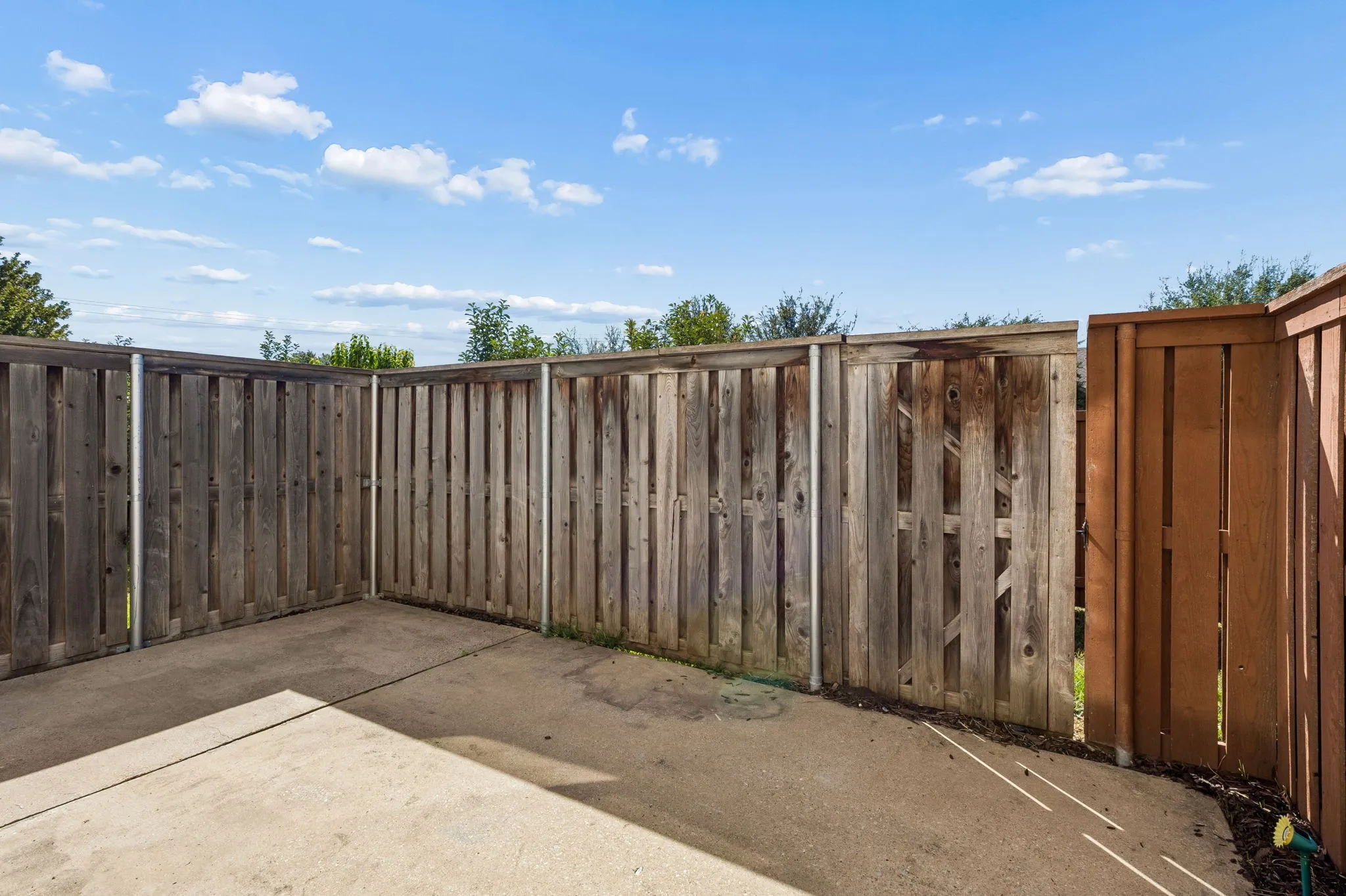 Concrete patio with privacy fencing and a dedicated gate