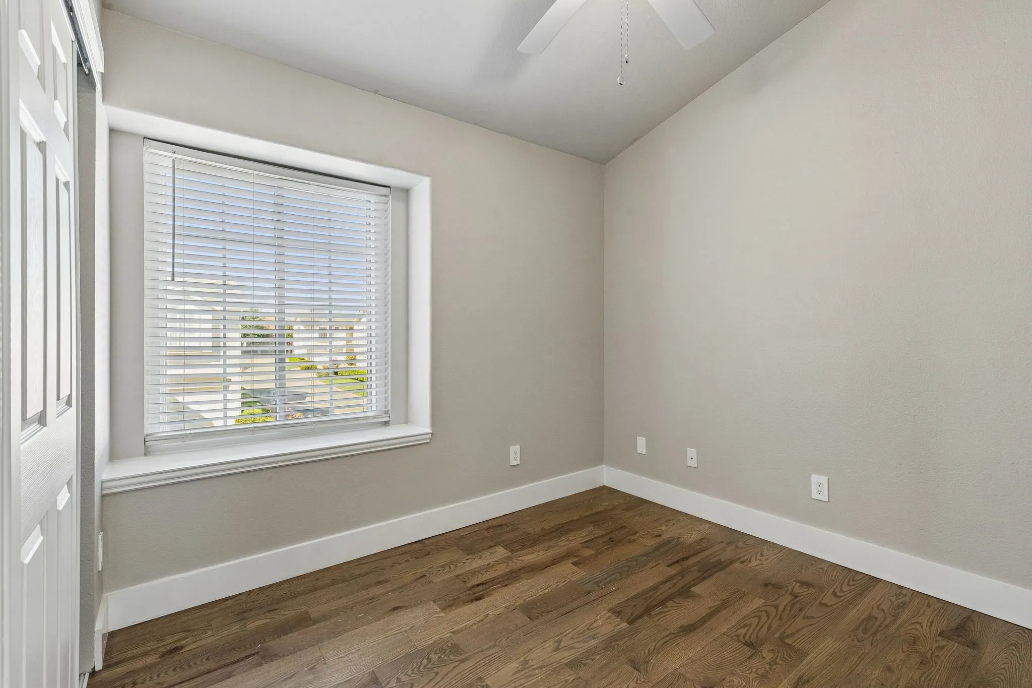 Hardwood flooring, window with blinds, ceiling fan, and white trim