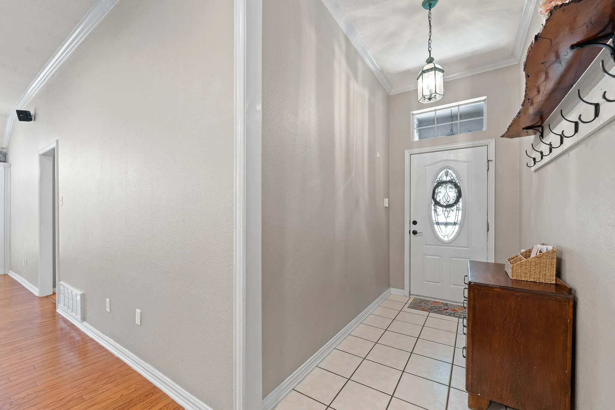 Entryway featuring a white paneled door with an oval glass insert, a transom window, and a hanging pendant light