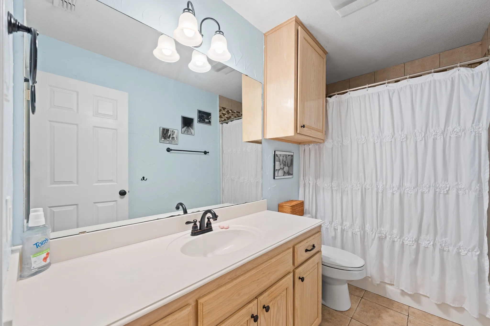 Vanity with an integrated sink, broad mirror, and warm wood-finish cabinetry