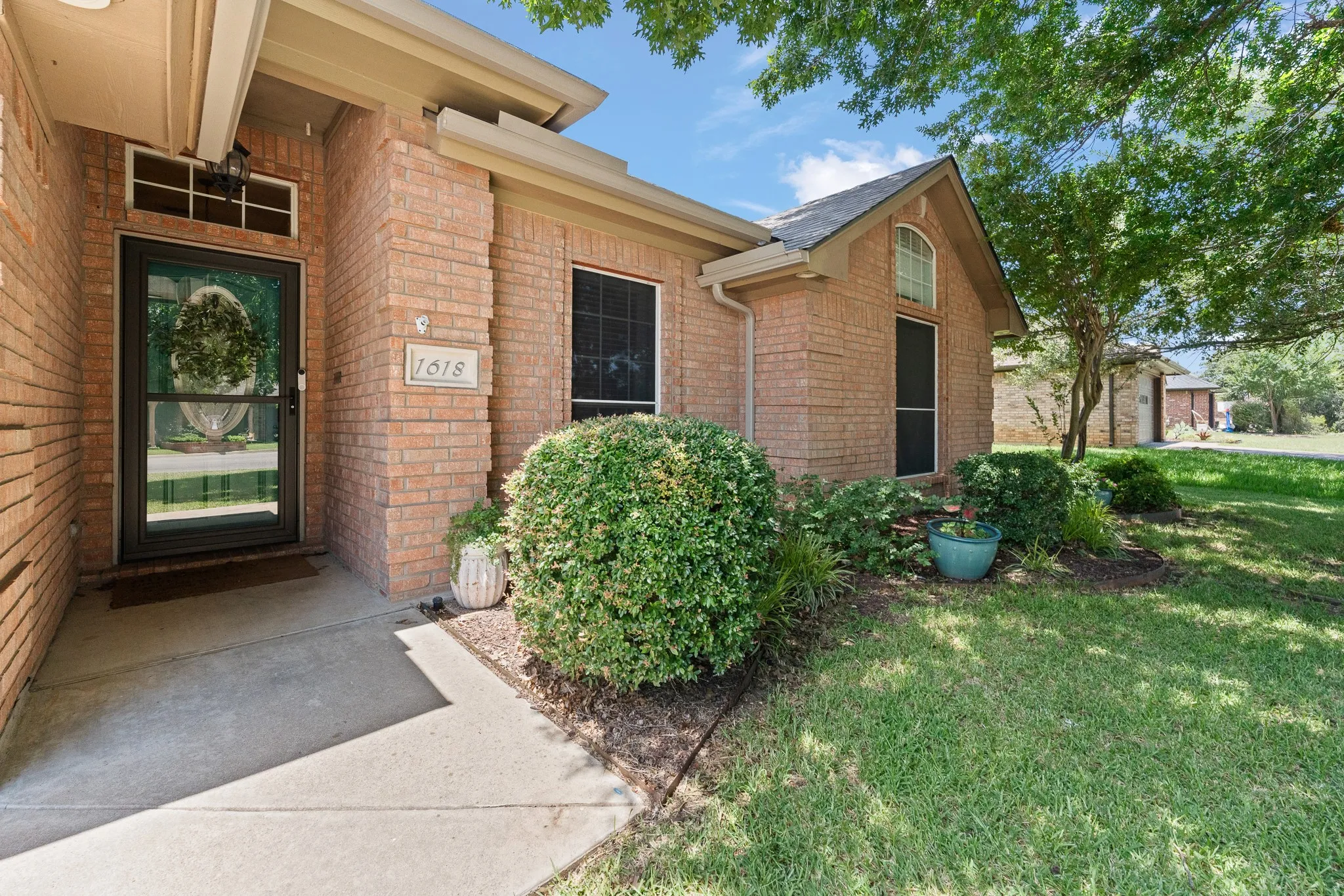 Brick exterior with a gabled roofline, covered entry, and established landscaping