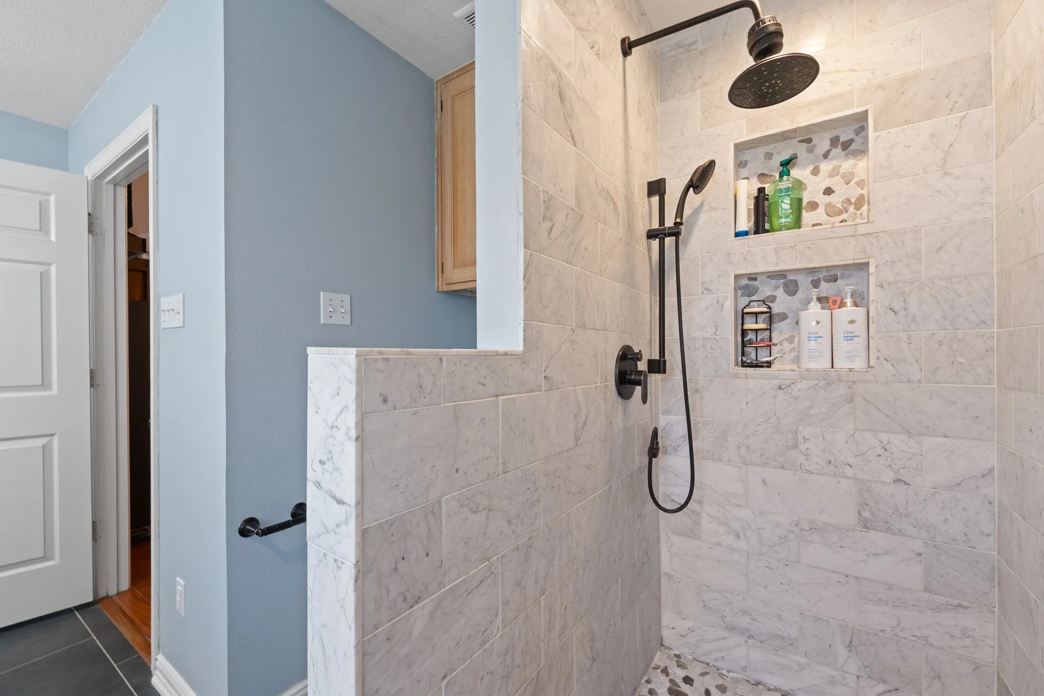 Tiled shower with a rain shower head, handheld shower, and integrated wall niches