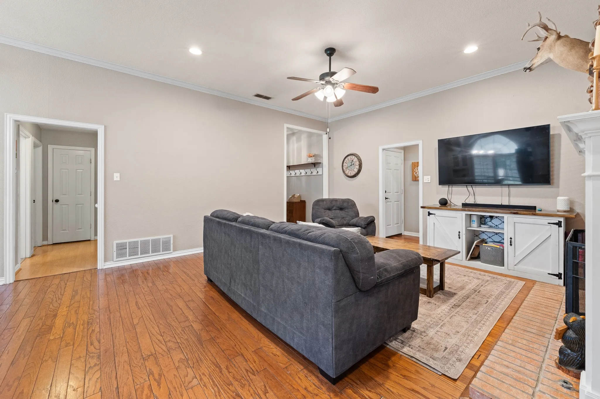 Wood-finish flooring, recessed lighting, crown molding, and a built-in media console with cabinet storage