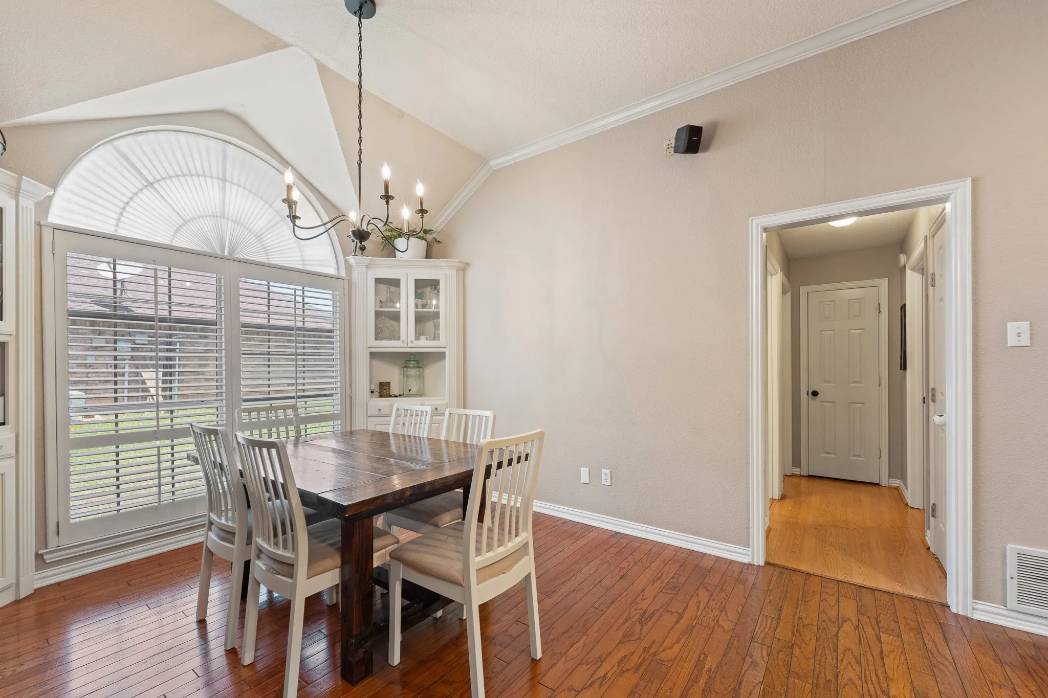 Vaulted ceiling with crown molding, wood-finish flooring, built-in cabinetry, and French doors with an arched transom window