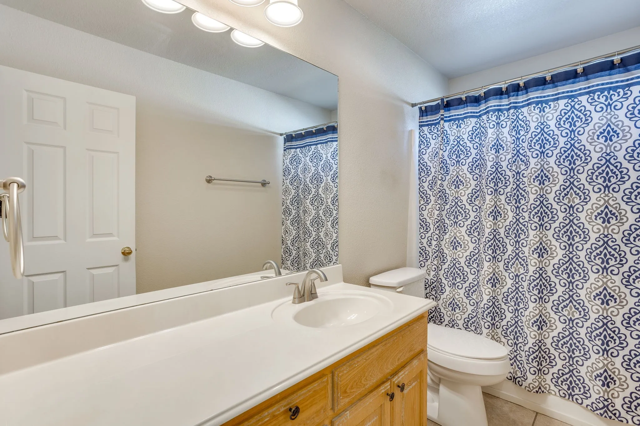 Bathroom featuring a single vanity with an integrated sink, brushed nickel faucet, and a large wall-mounted mirror