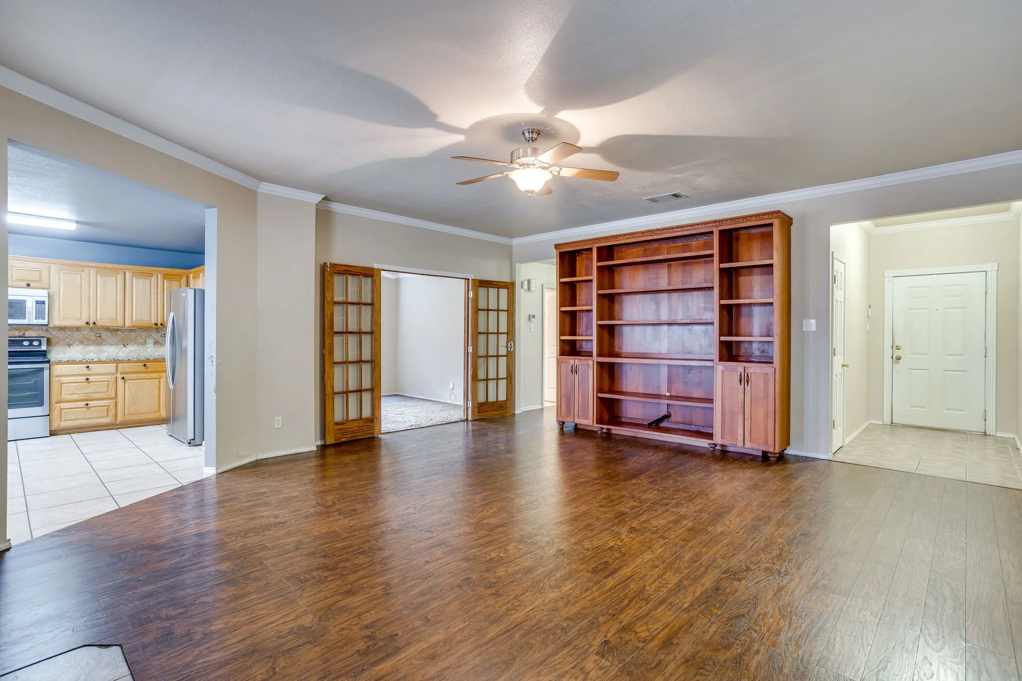 Wood-finish flooring throughout the main living space, built-in wooden shelving unit, recessed lighting, and crown molding