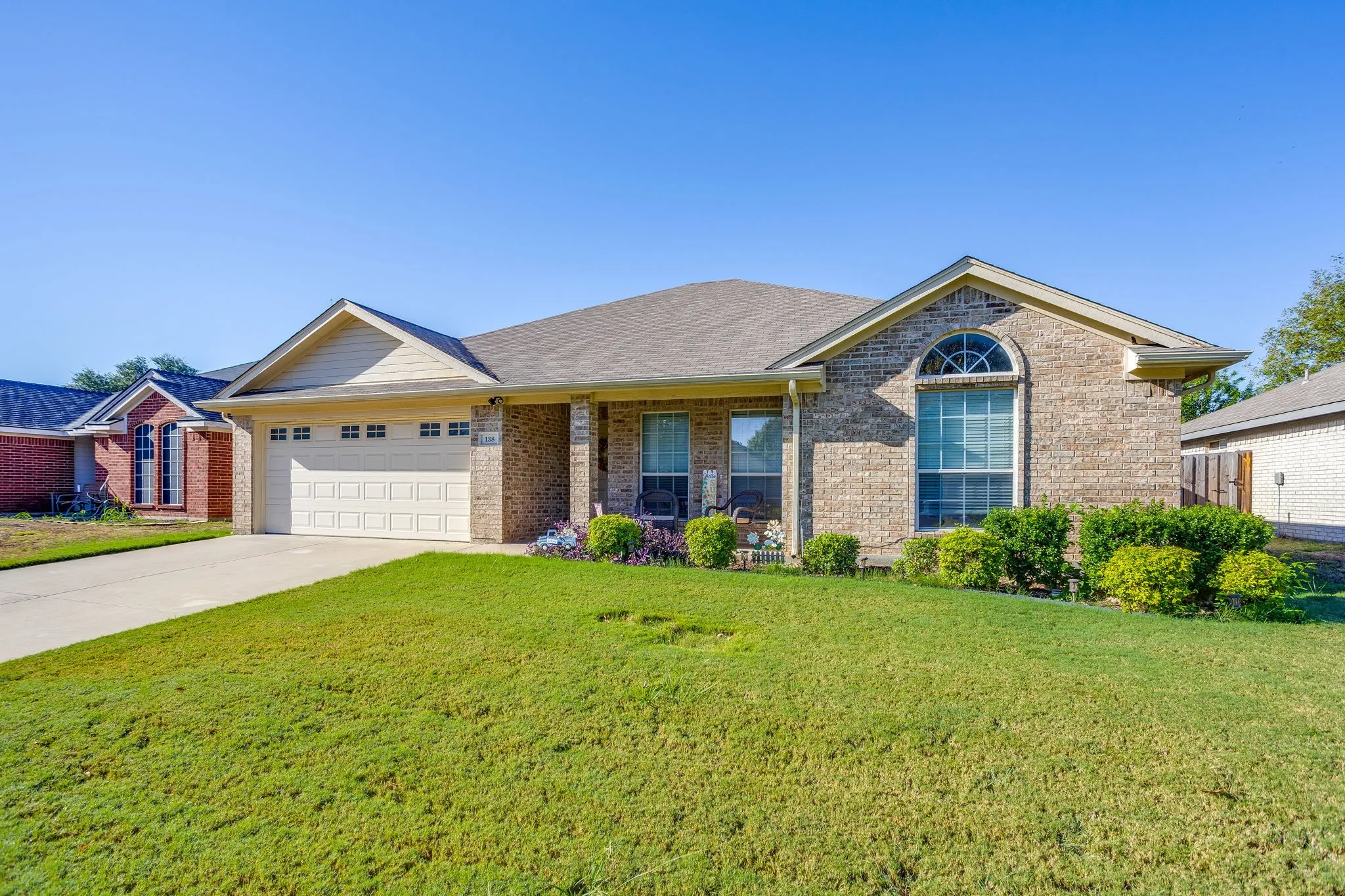 Brick facade, arched window, attached garage, covered front porch, concrete driveway