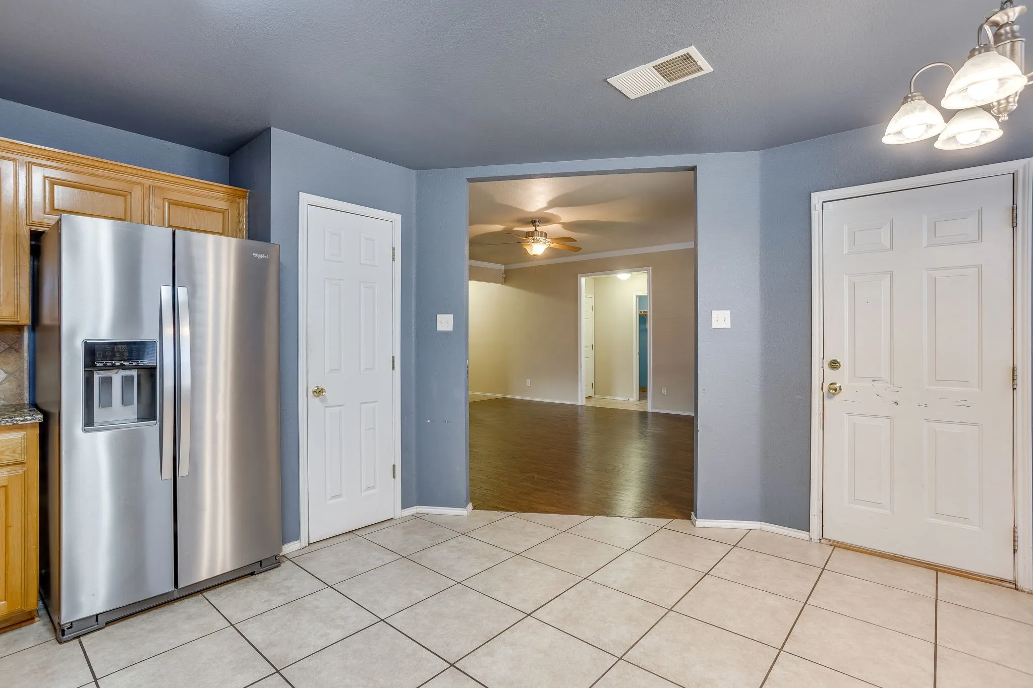 Tile flooring throughout, natural wood cabinetry, and a ceiling-mounted light fixture