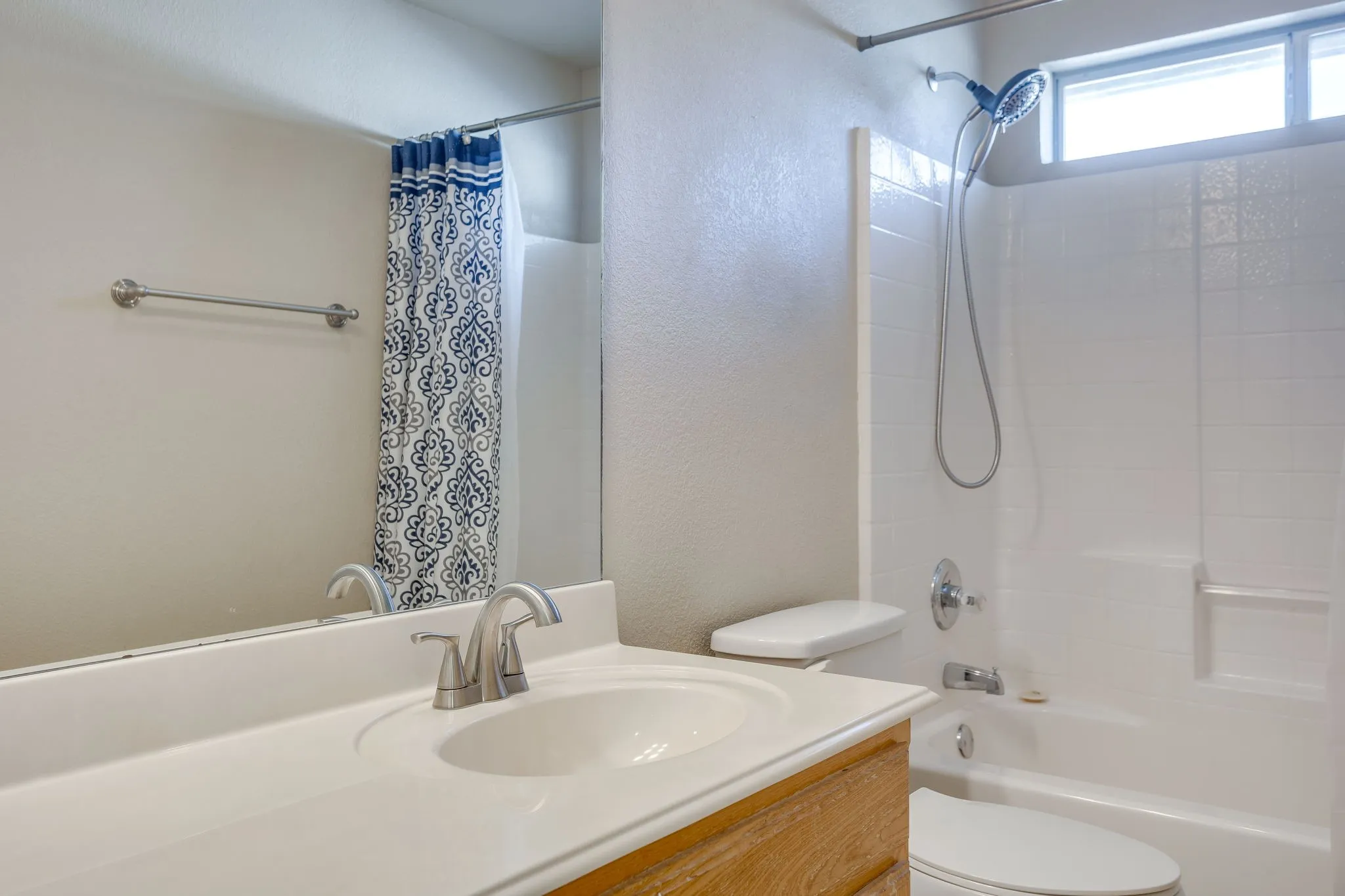 Bathroom featuring a wood-finish vanity, integrated sink, and brushed nickel faucet