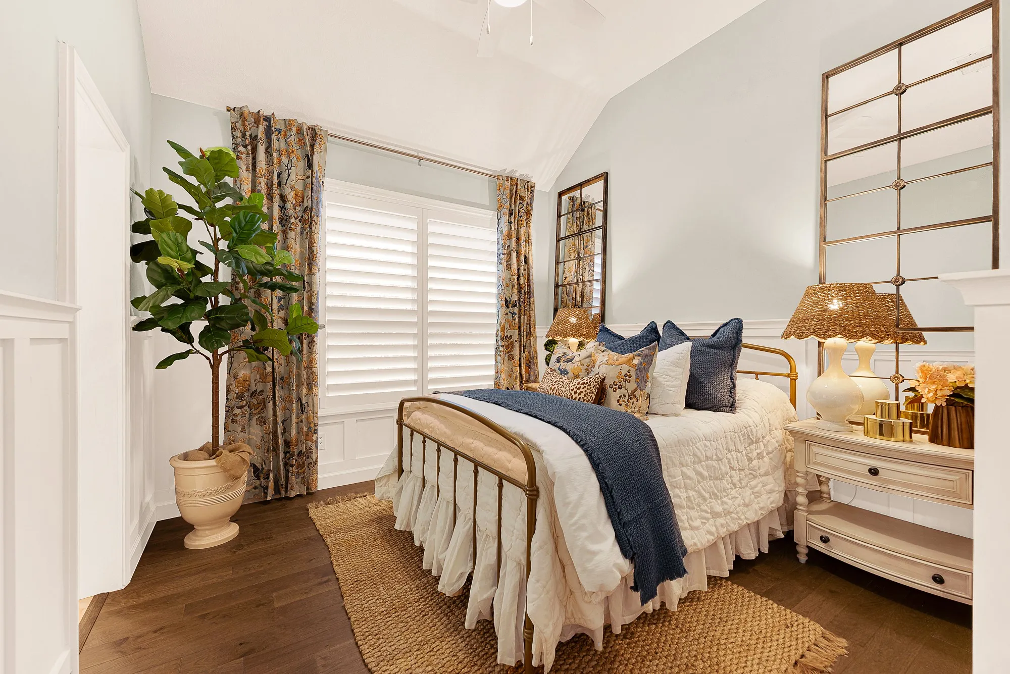 Bedroom 2 features beautiful wainscoting and millwork detail that grounds the room under a soaring vaulted ceiling, catching soft daylight through shuttered windows. Welcome overnight guests to a serene haven where  hey can instantly unwind and recharge.