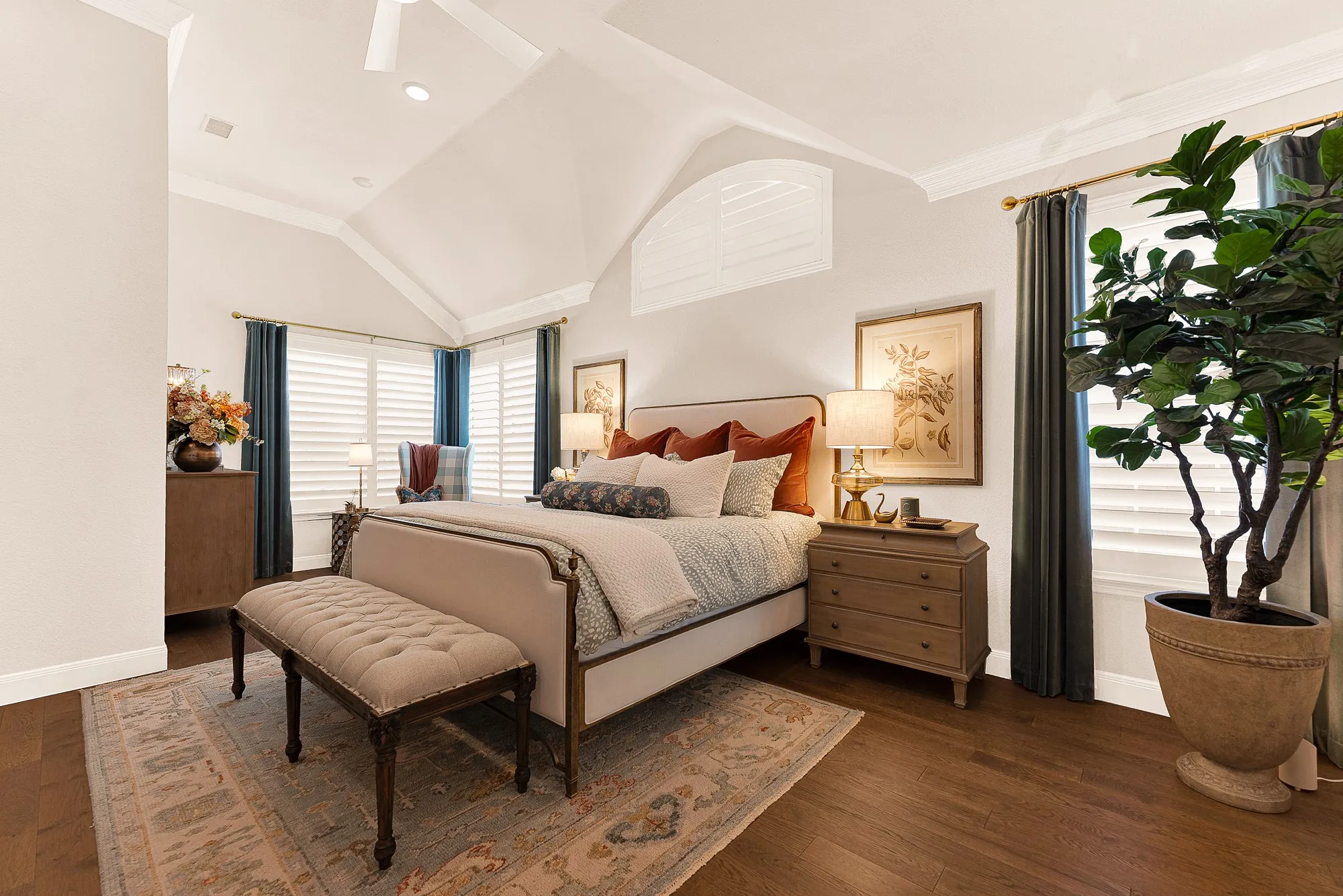 A sunlit sitting area in primary bedroom with views of backyard and pool captures bright natural light through shuttered windows. Savor a quiet morning coffee while taking in serene poolside vistas