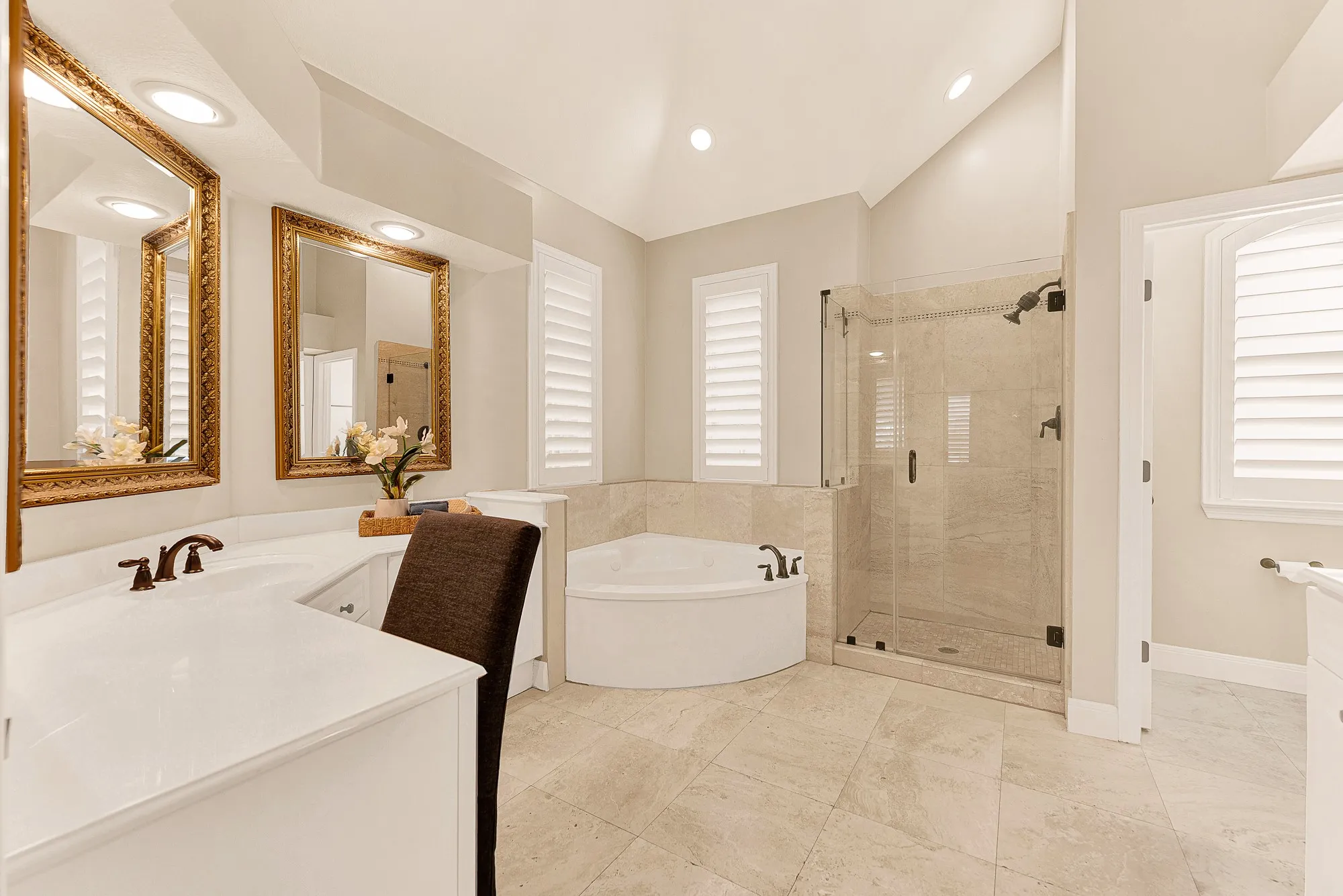 High vaulted ceilings and crisp neutral tile amplify soft light throughout the ensuite bath. Picture preparing for the day ahead in a bright, spa-inspired sanctuary.