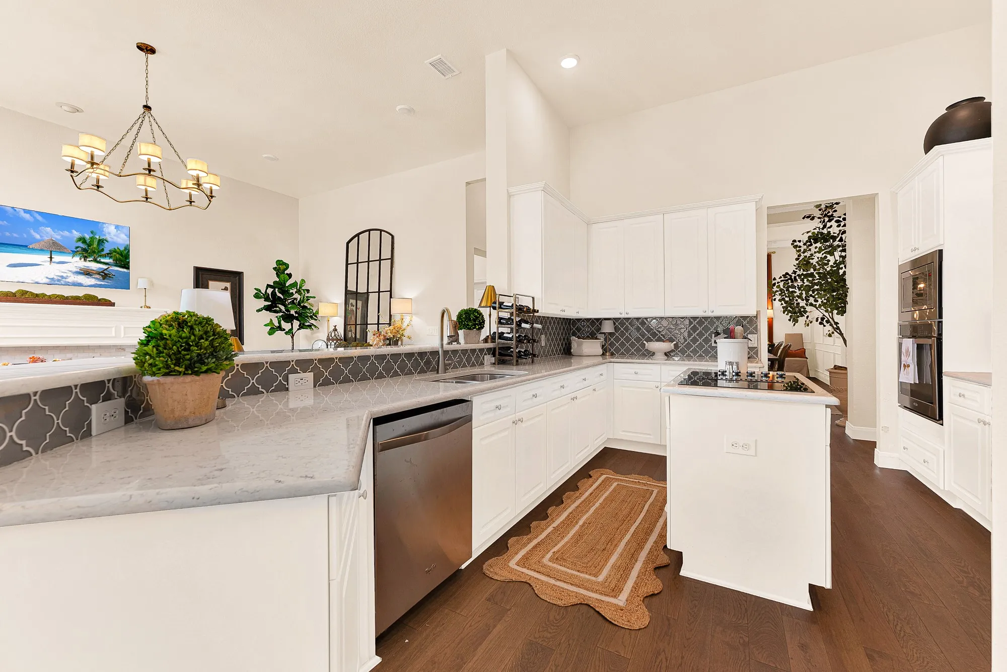 Generous quartz counters wrap around the perimeter, creating a sweeping workspace bathed in bright ambient ceiling light. Prep weeknight meals effortlessly while staying connected with family hanging out nearby.