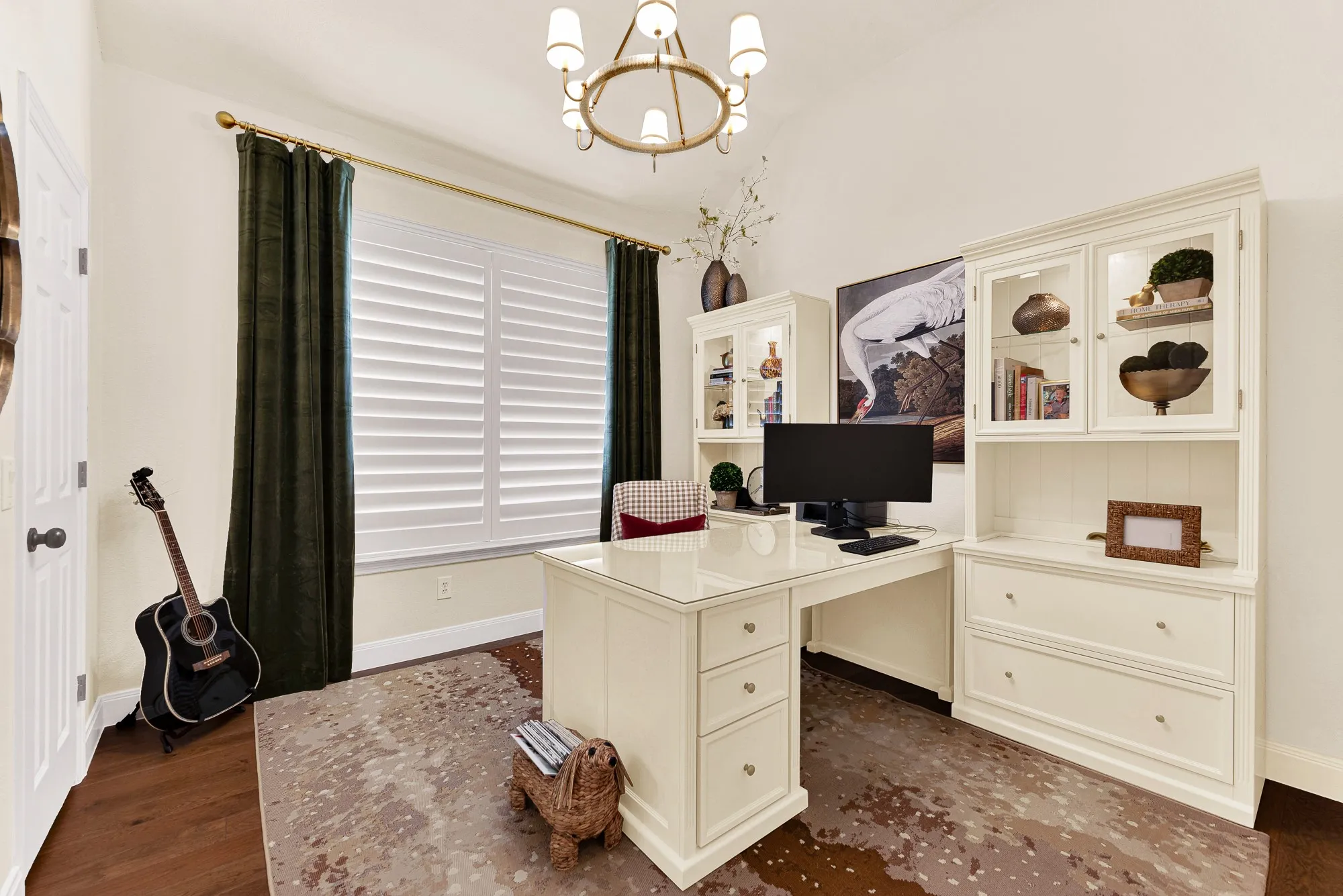 A grand picture window with plantation shutters bathes this versatile room in steady natural light beneath a classic central fixture. Visualize focusing on creative projects or working remotely in a quiet, sunlit workspace.