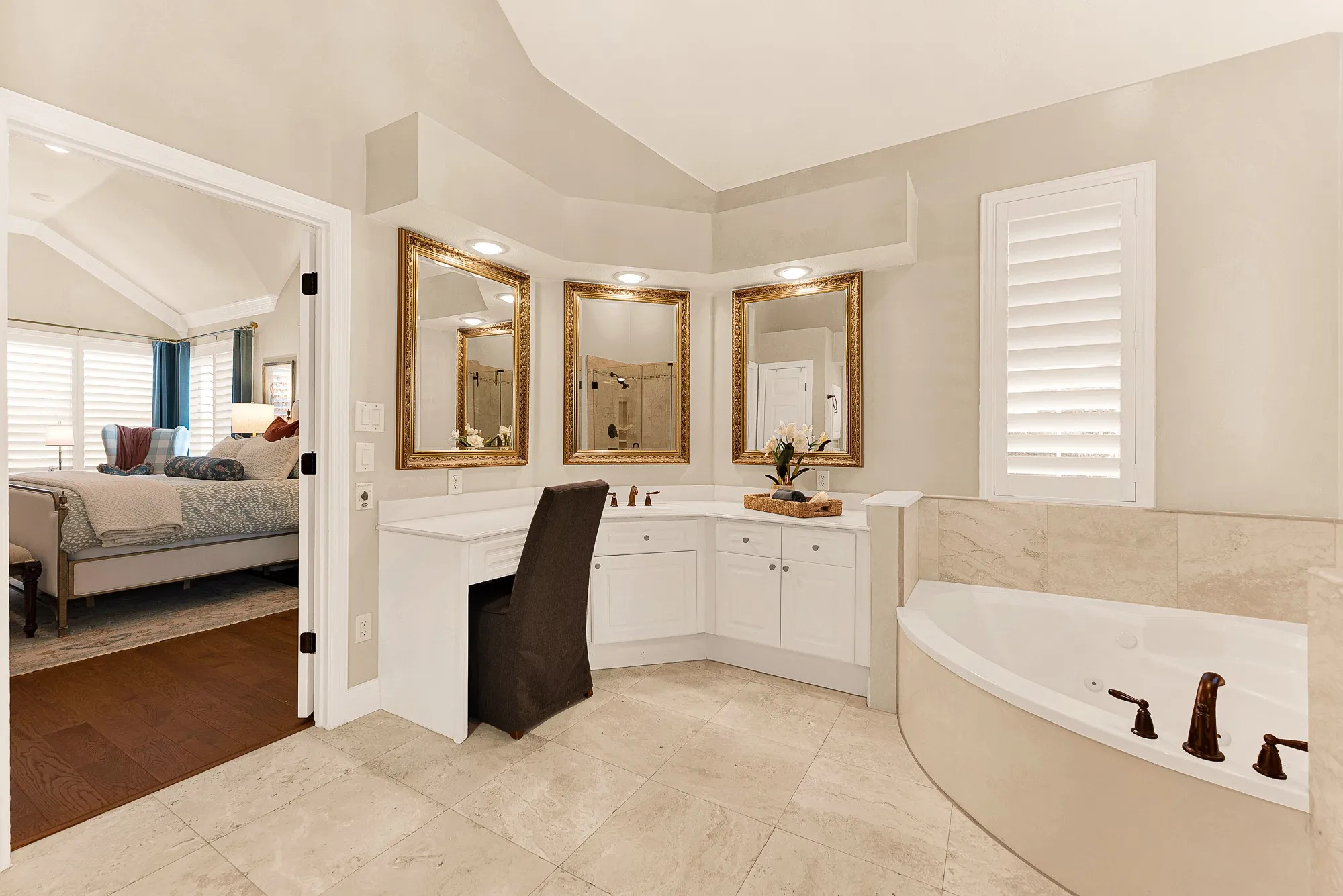 An expansive wrap-around vanity with framed mirrors creates a dedicated grooming area reflecting warm ambient light. Imagine taking time for a pampering evening skincare routine before turning in.