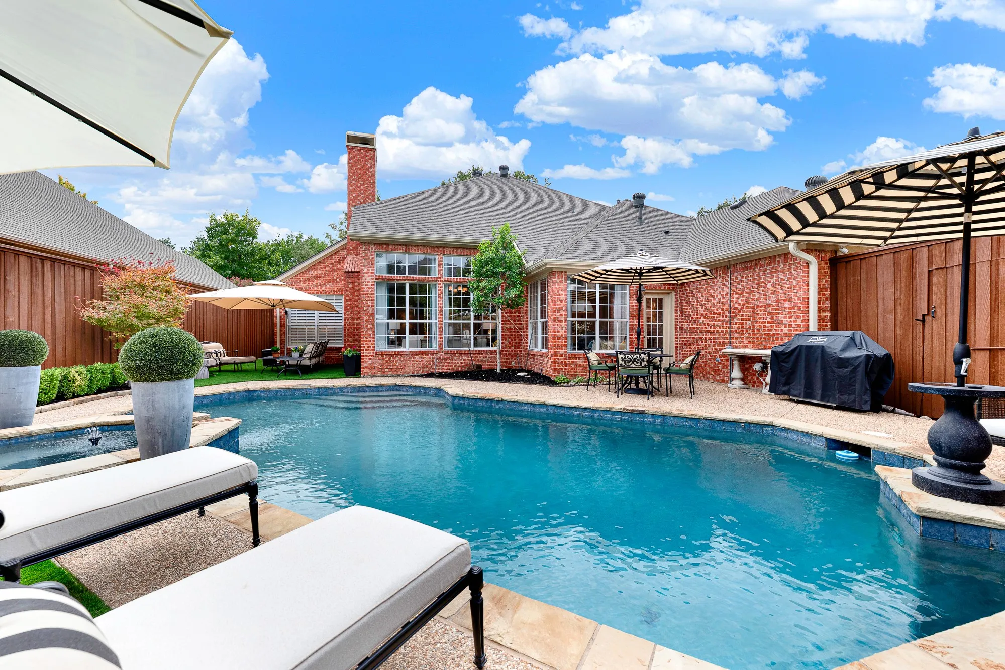 An expansive pea-gravel deck wraps around the pool, backed by a pool pump housing replaced in 2024 for worry-free operation. Unwind after work while listening to the tranquil spillover fountain into the main poo