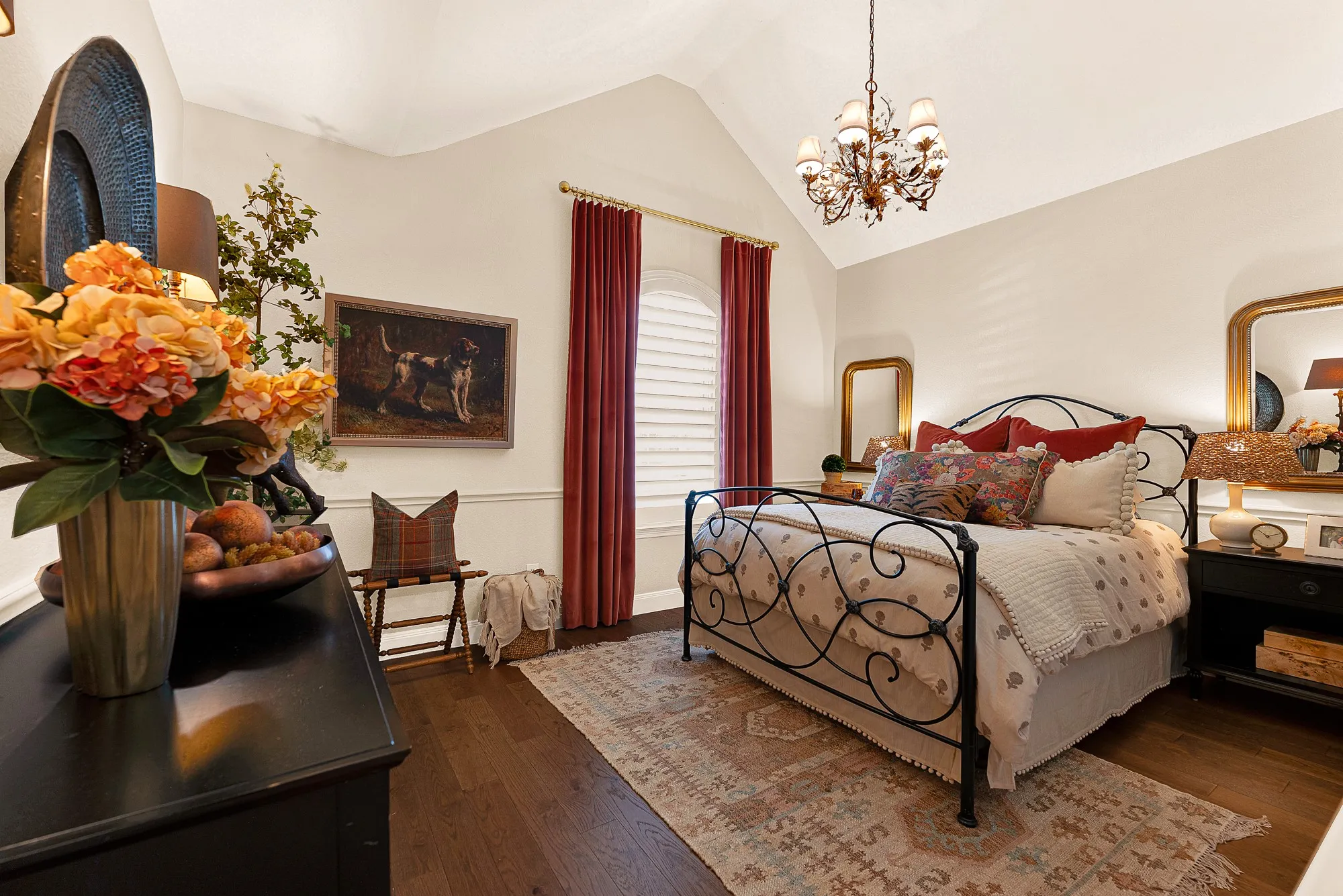 An elegant arched window and high pitch ceiling give this bedroom dramatic vertical scale illuminated by a classic chandelier. Enjoy cozy evening downtime surrounded by calm, inviting architectural character.