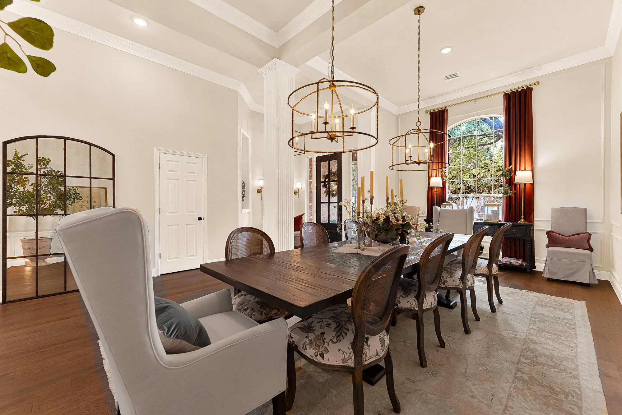 A grand arched window creates an elegant focal point, pouring warm sunlight across the detailed wall trim and high ceilings. Imagine lingering over Sunday brunch with family while enjoying peaceful morning garden views.