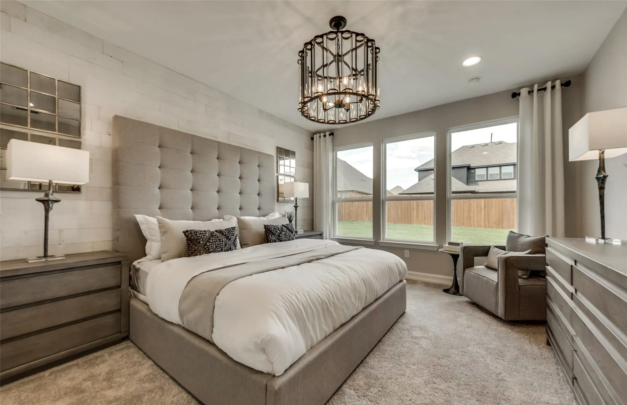 Wall-to-wall carpeting, three large windows, a decorative chandelier, and a shiplap accent wall