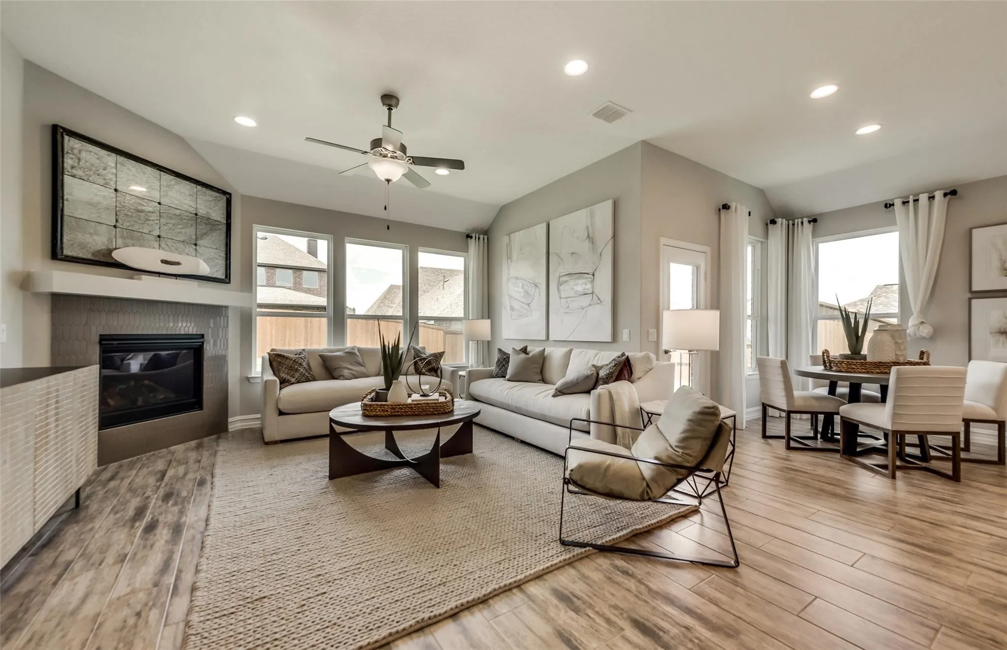 Open-concept living area with wood-finish flooring, a fireplace, vaulted ceilings, recessed lighting, and a ceiling fan