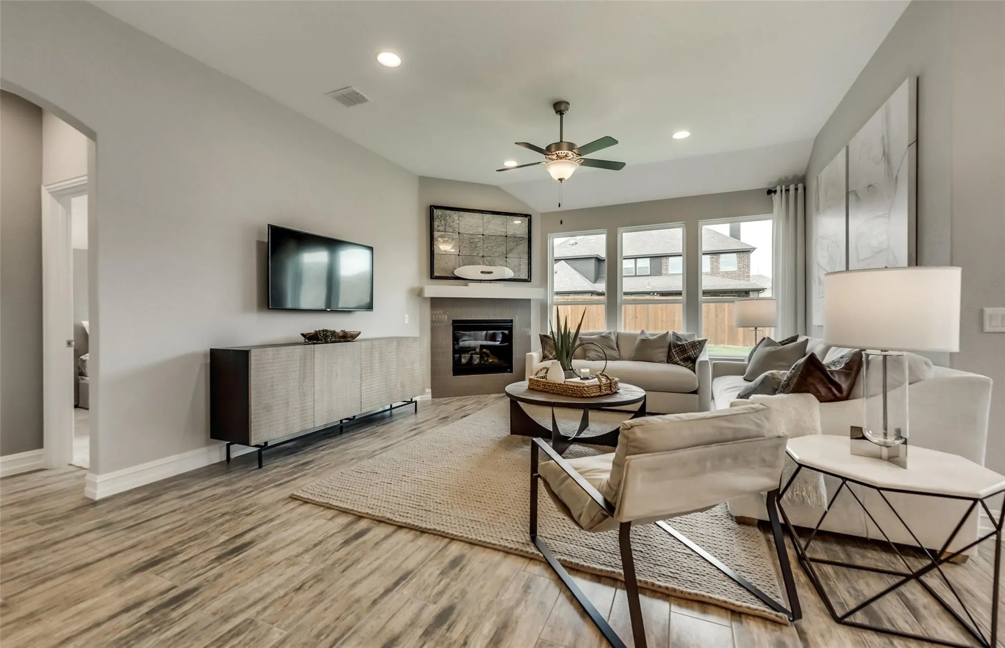 Wood-finish flooring, recessed lighting, and a corner fireplace with a mantel