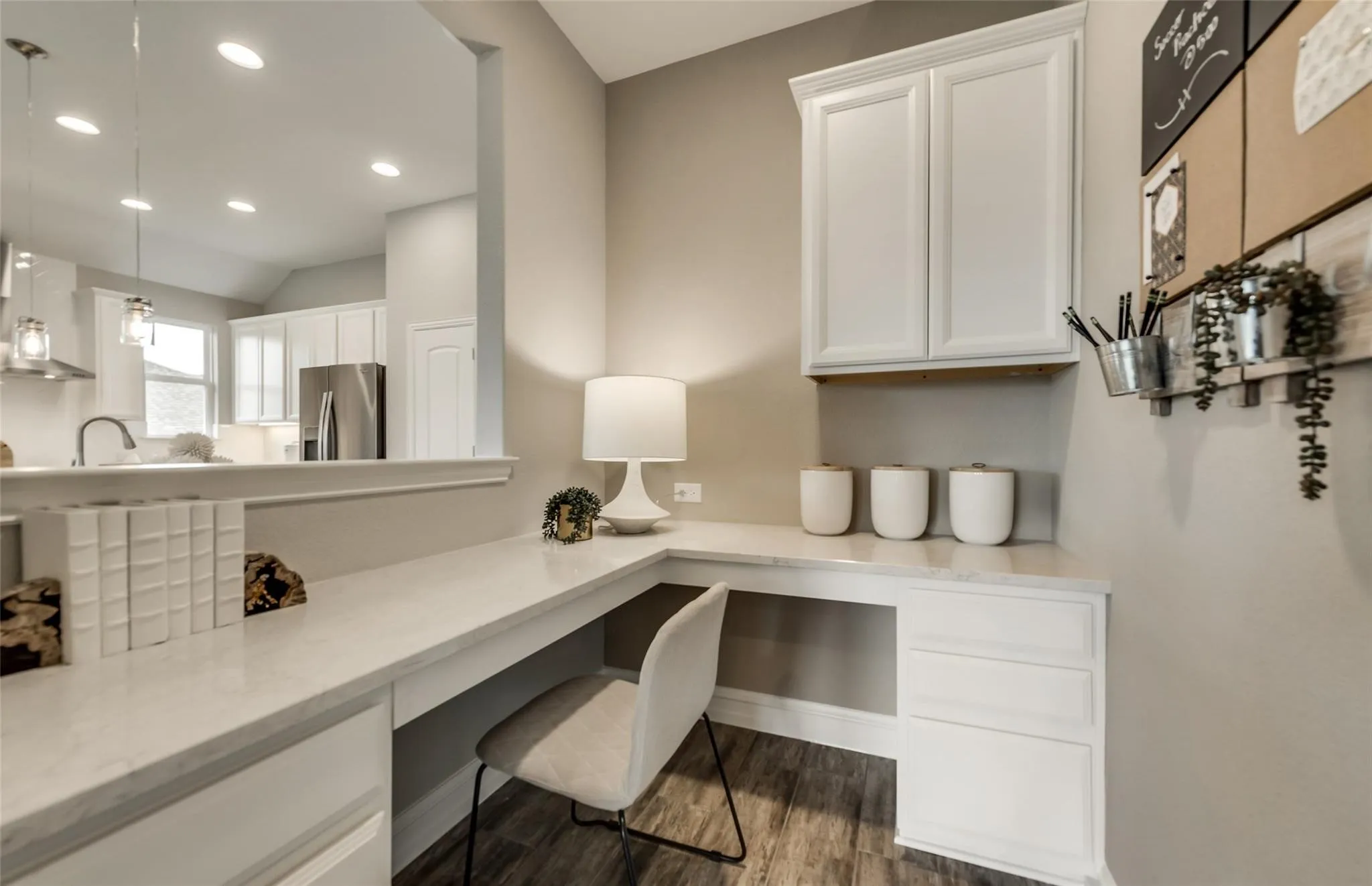 Built-in desk with a light-toned countertop, white cabinetry, and wood-finish flooring