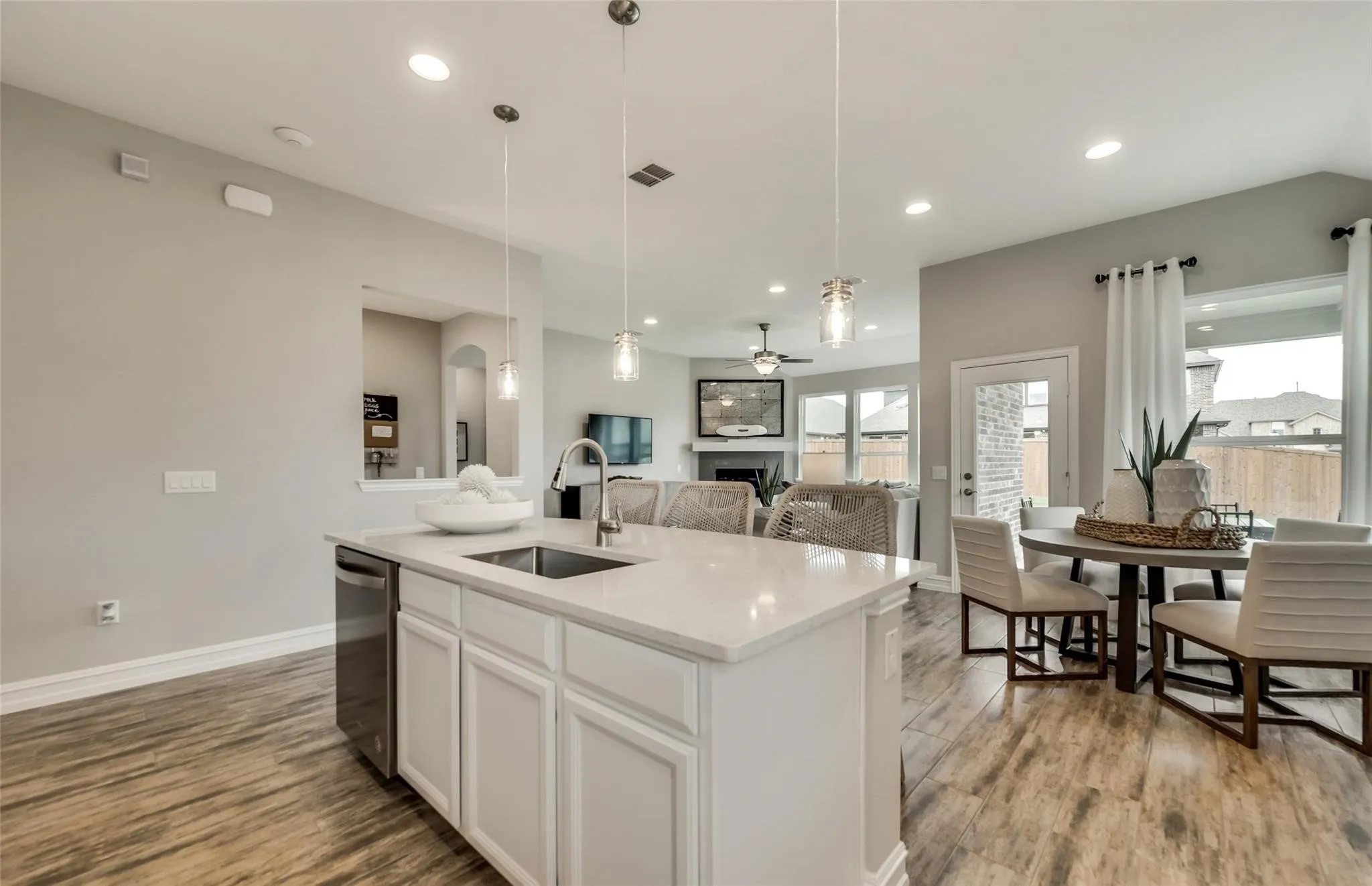 Open-concept living space with wood-finish flooring, recessed lighting, and a kitchen island featuring a stainless steel sink and appliance