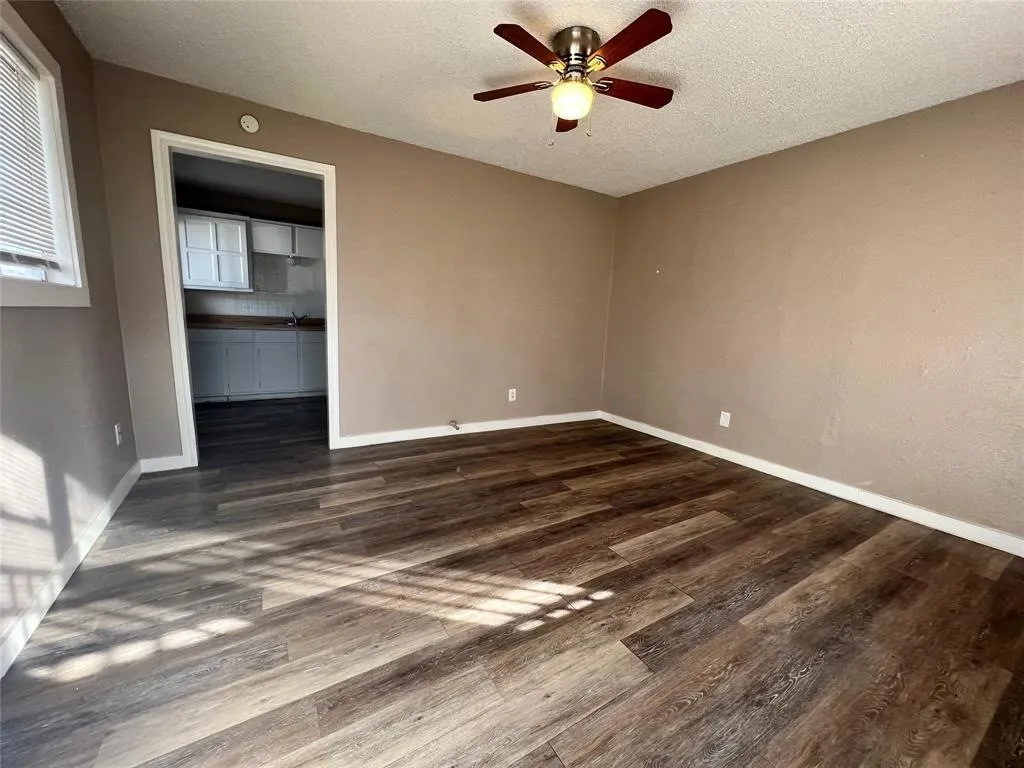 Wood-finish flooring throughout, ceiling fan with integrated lighting, and neutral wall tones