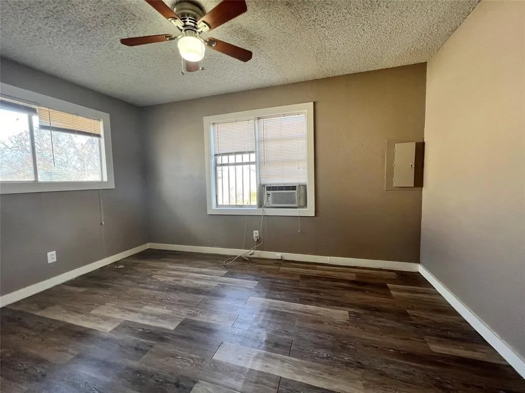 Wood-finish flooring, ceiling fan with integrated lighting, window-mounted air conditioning unit, and multiple​​‌​​​​‌​​‌‌​‌‌​​​‌‌​‌​‌​‌​​​‌​​ windows