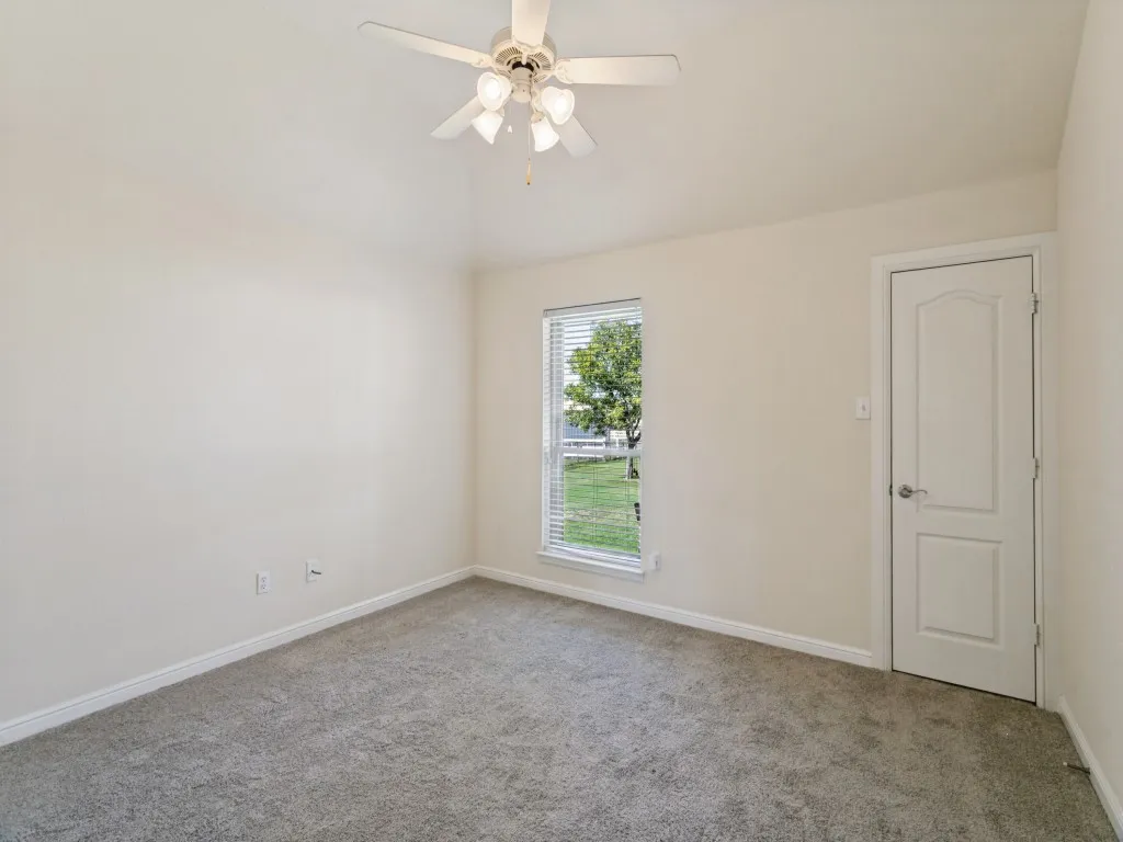 Vaulted ceiling with a ceiling fan, carpeted flooring, and a single window with blinds