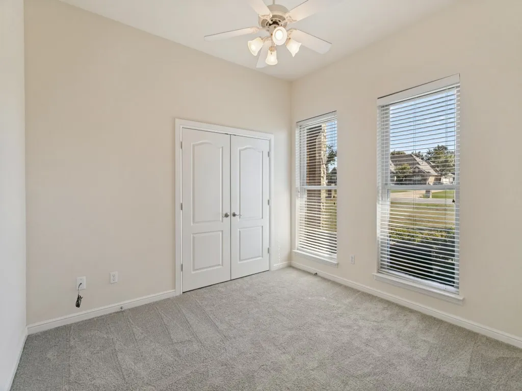 Recessed ceiling, neutral wall paint, two windows with blinds, gray carpet, and a ceiling fan