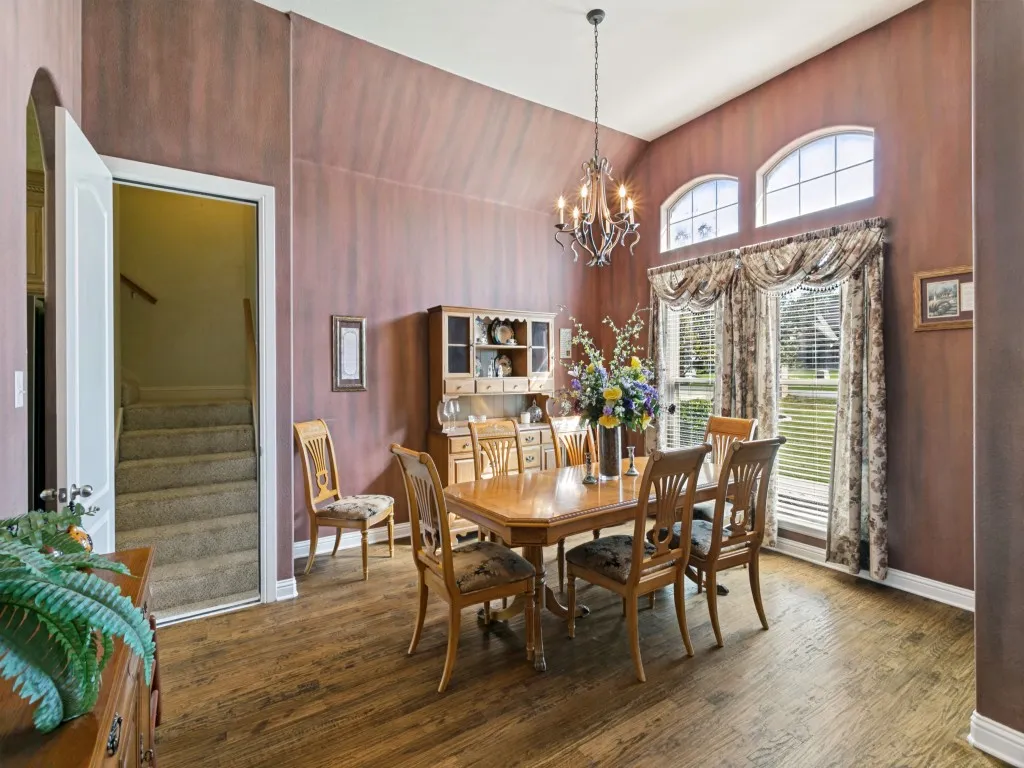 Vaulted ceiling, wood-finish flooring, arched windows, chandelier, and a built-in hutch
