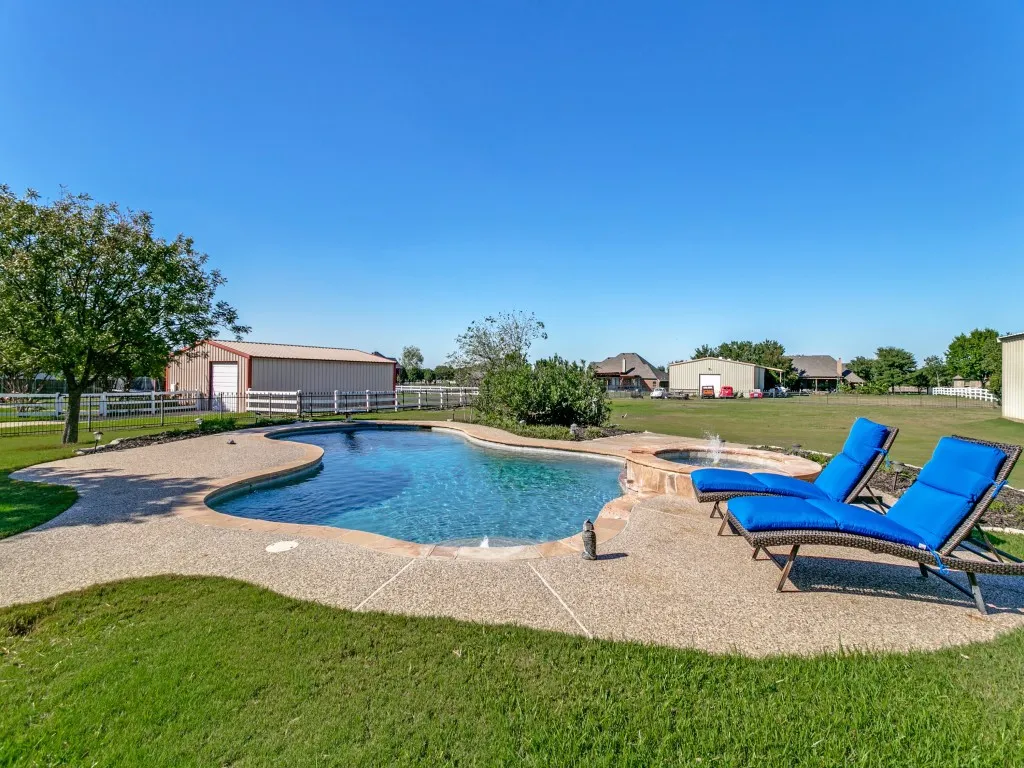 Freeform swimming pool with integrated spa and exposed aggregate decking