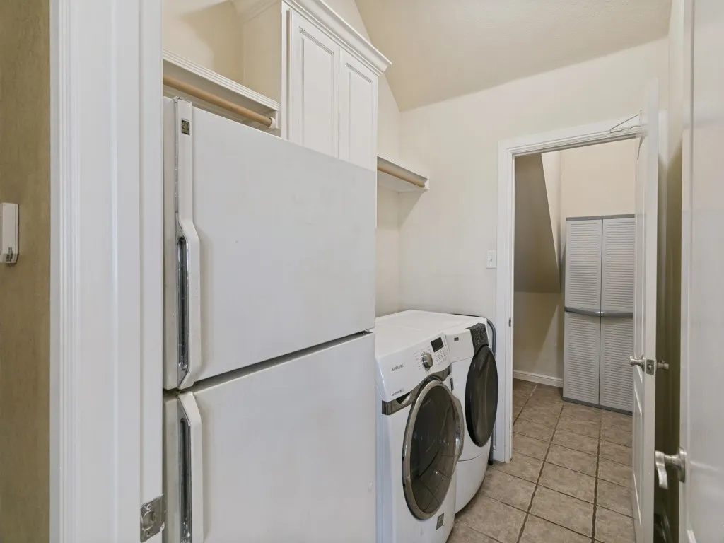 Laundry area featuring upper cabinetry, a wood-finish hanging rod, and tile flooring