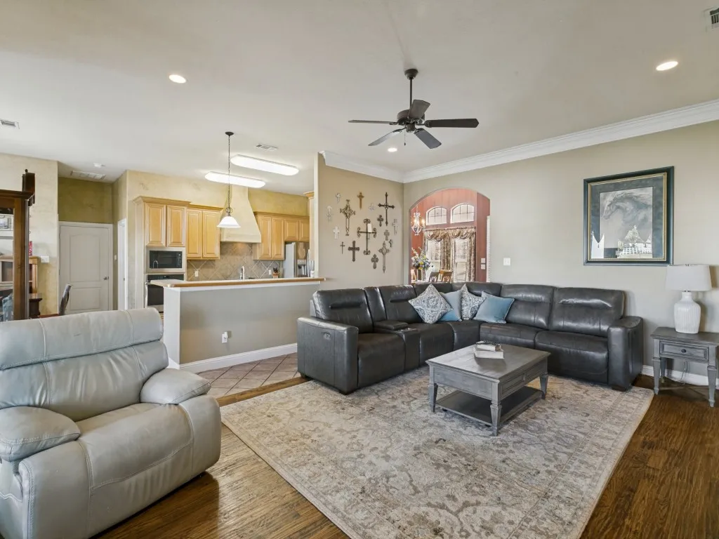 Open-concept living area with wood-finish flooring, recessed lighting, and crown molding