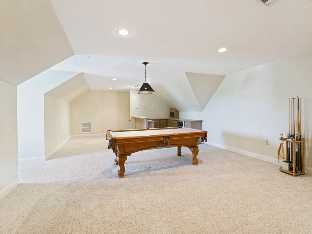 Spacious bonus room featuring neutral carpeting, recessed ceiling lighting, a pendant fixture, and a built-in wet bar with cabinetry