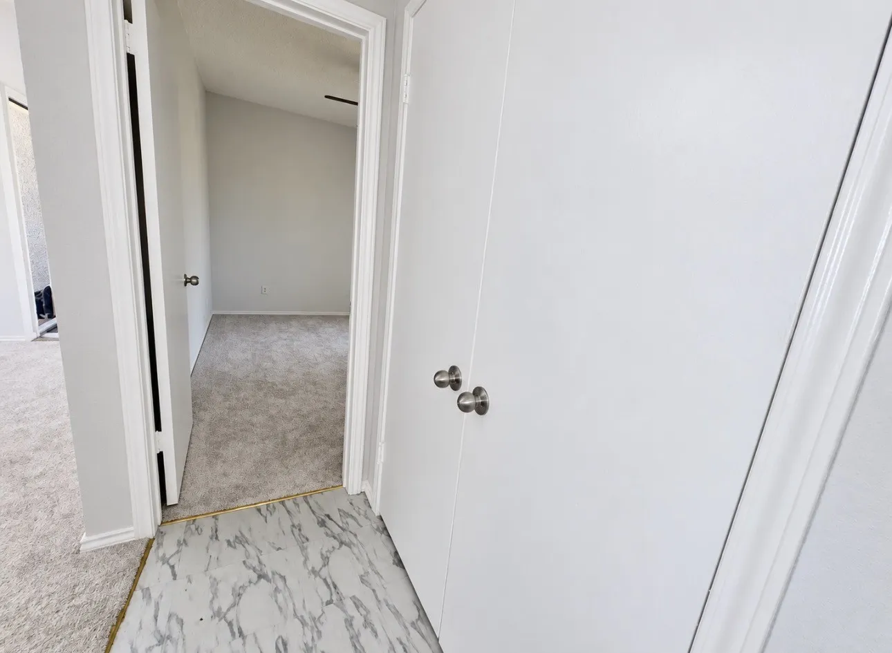 Interior features include clean white doors with brushed nickel hardware, light grey textured carpeting, and white trim