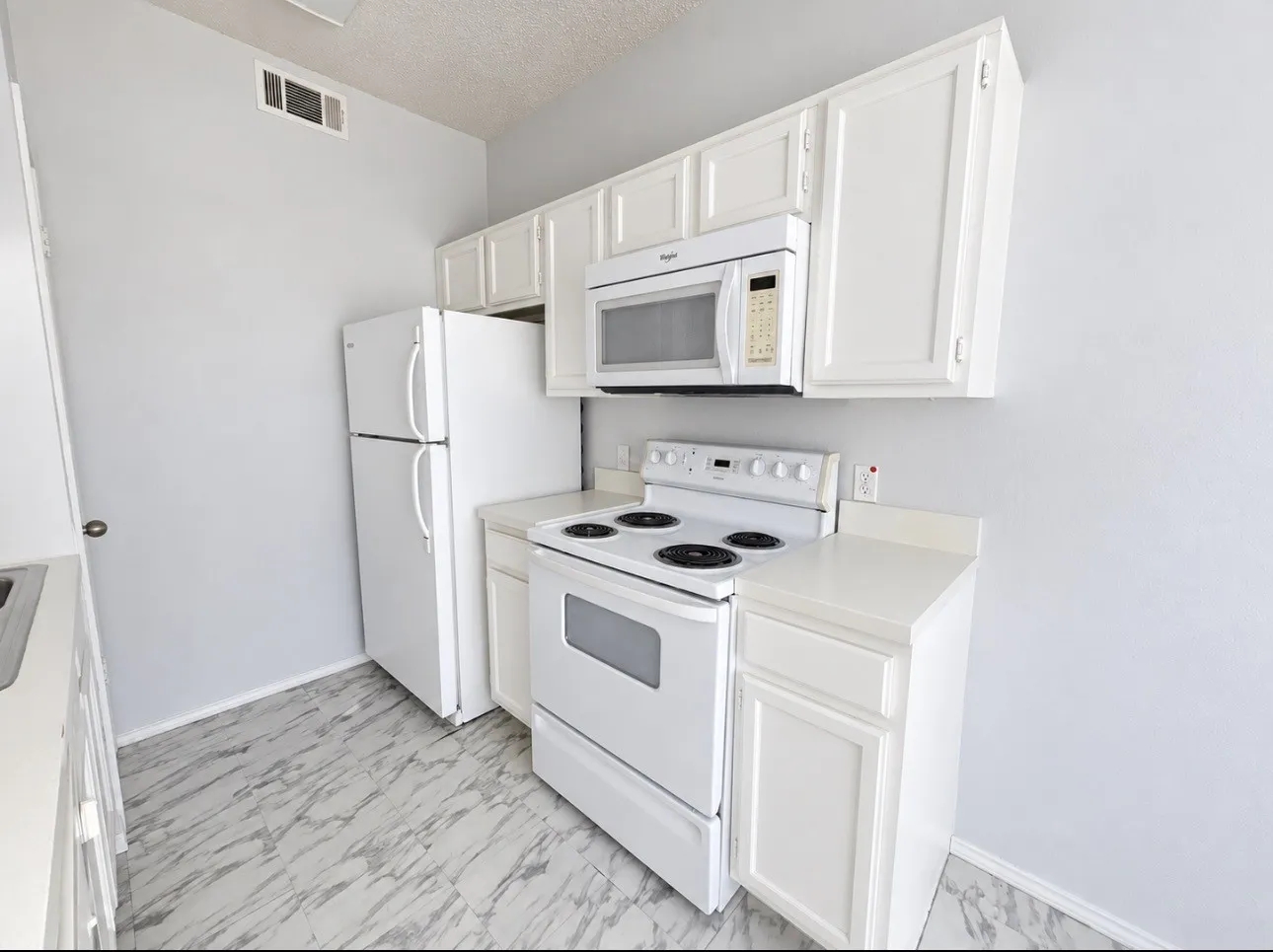 White cabinetry, white appliances, white countertops, white walls, and marble-look flooring