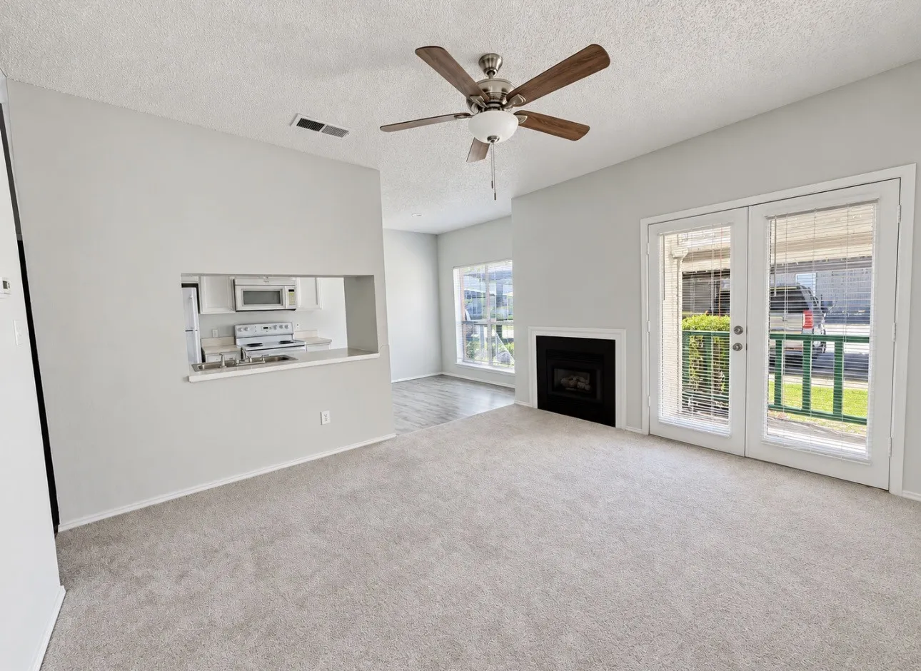 Carpeted living area with a ceiling fan, fireplace, and glass patio doors