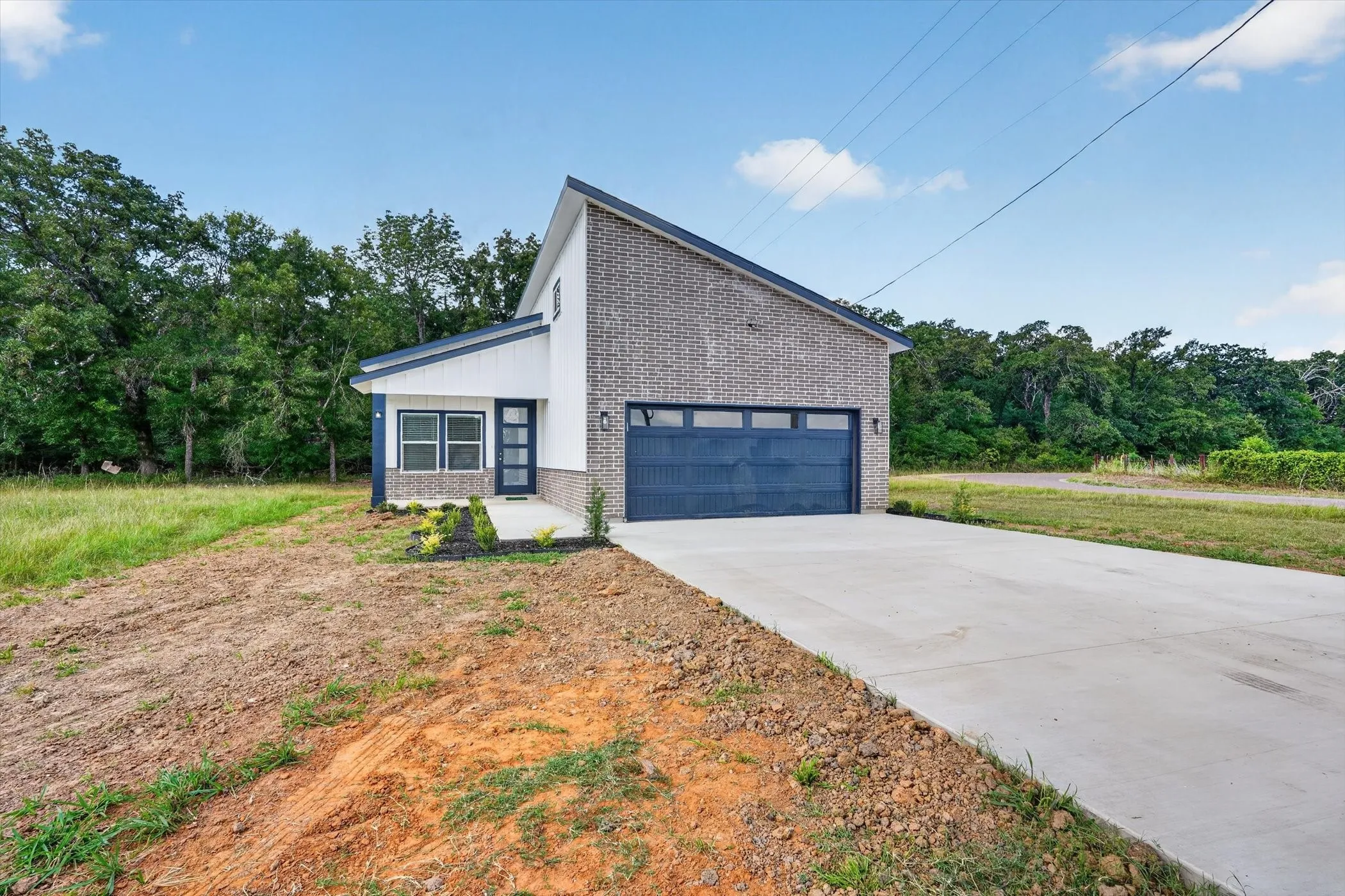 Contemporary exterior featuring brick and horizontal siding, an attached two-car garage, a concrete driveway, and a covered entry