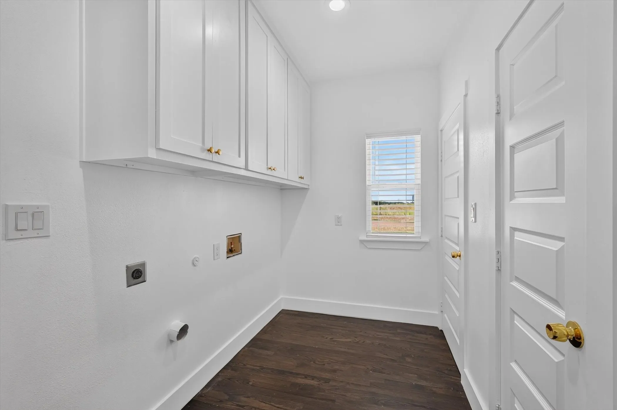 White cabinetry with gold-tone hardware, wood-finish flooring, recessed lighting, white paneled doors, and a window with blinds