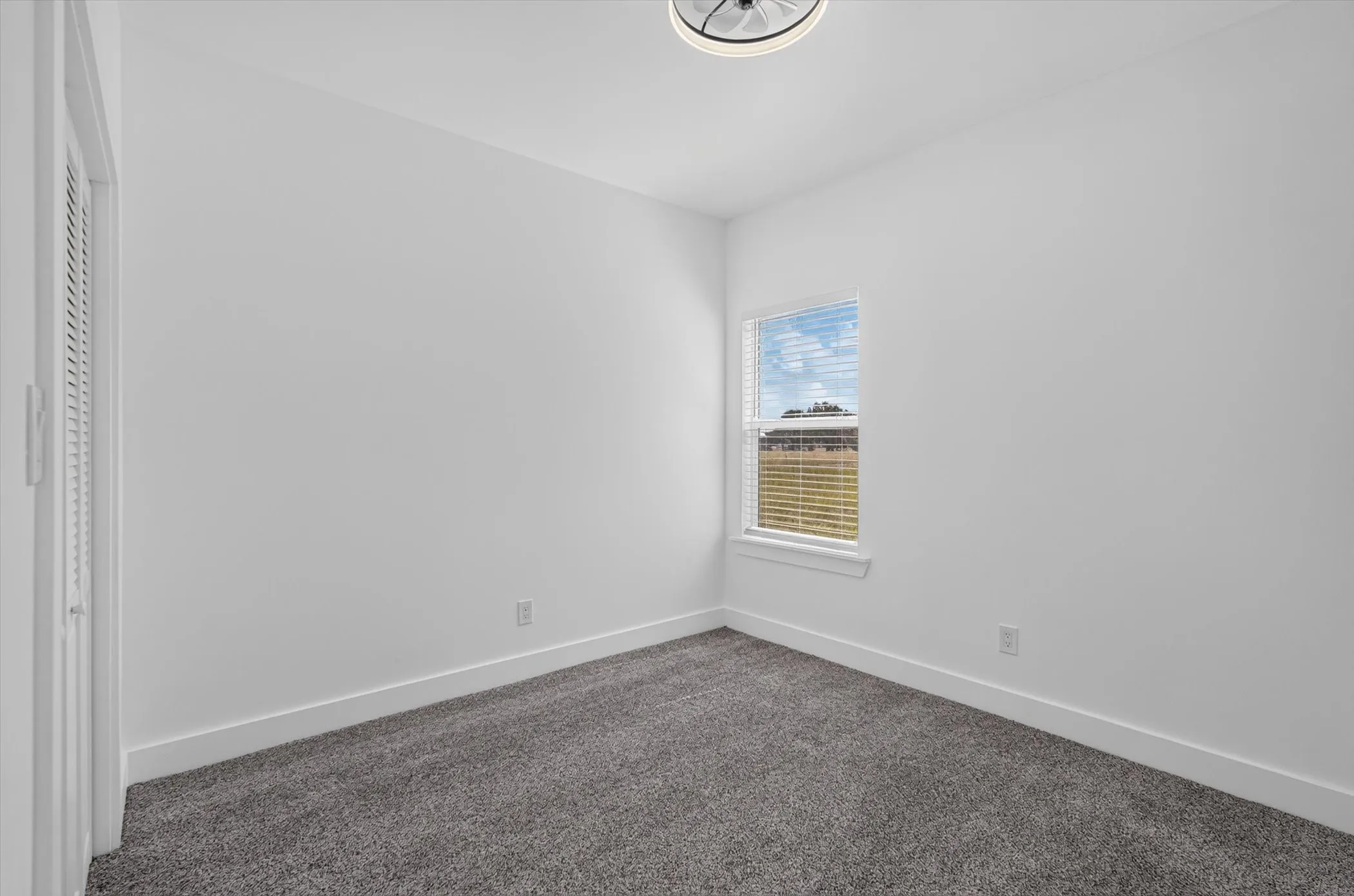 Neutral wall paint, gray carpet flooring, recessed window, and white window blinds
