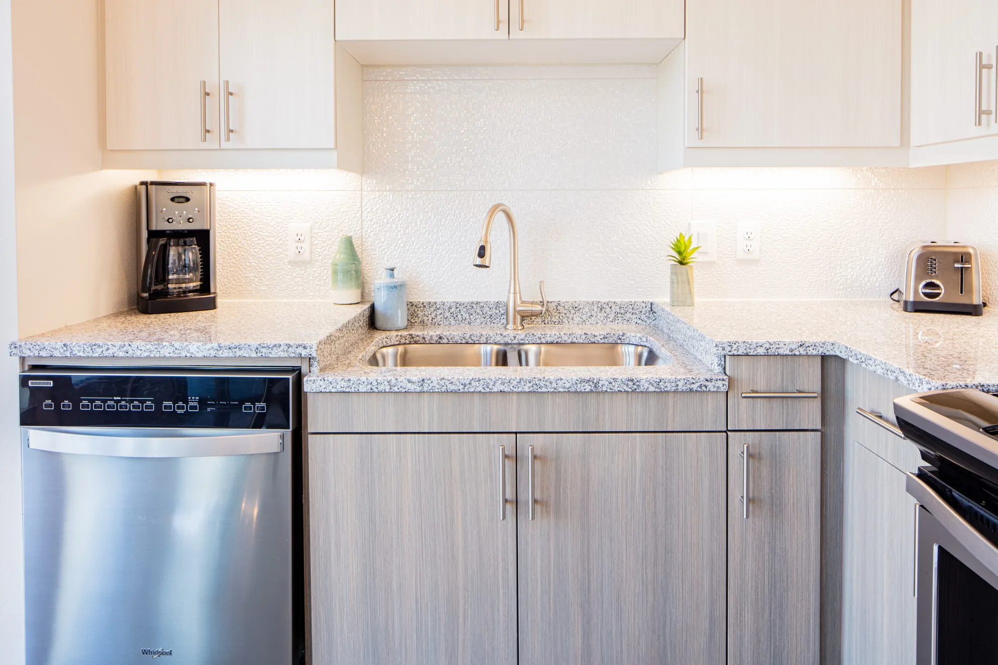 Kitchen featuring sink, stainless steel dishwasher, light stone countertops, tasteful backsplash, and range