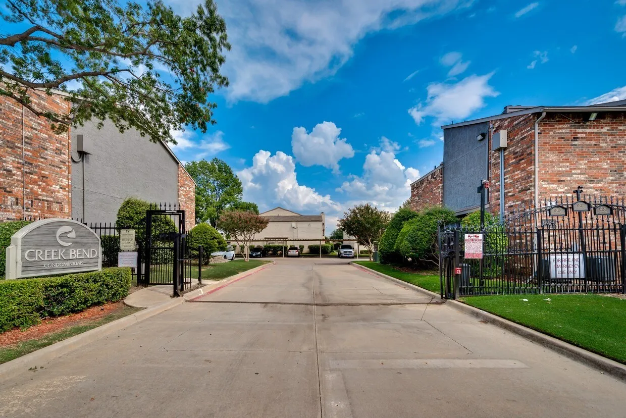 Gated entry with wrought iron fencing and brick pillars