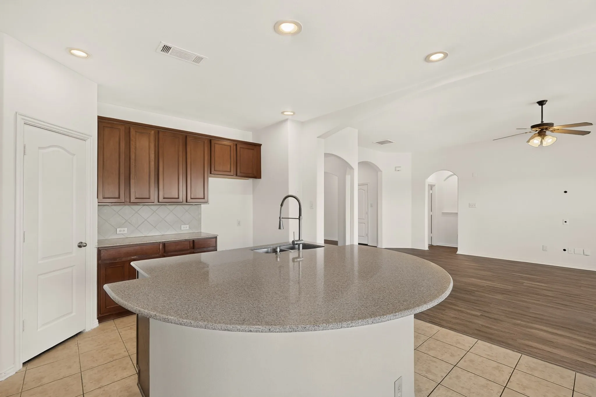 Kitchen featuring a curved island with countertop, stainless steel sink, and gooseneck faucet