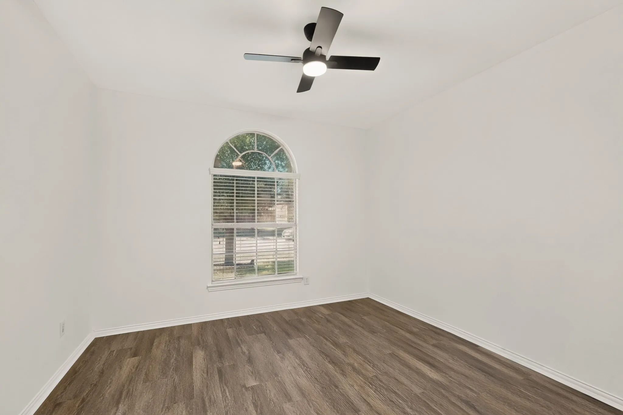 Arched window with blinds, wood-finish flooring, and a ceiling fan with integrated lighting