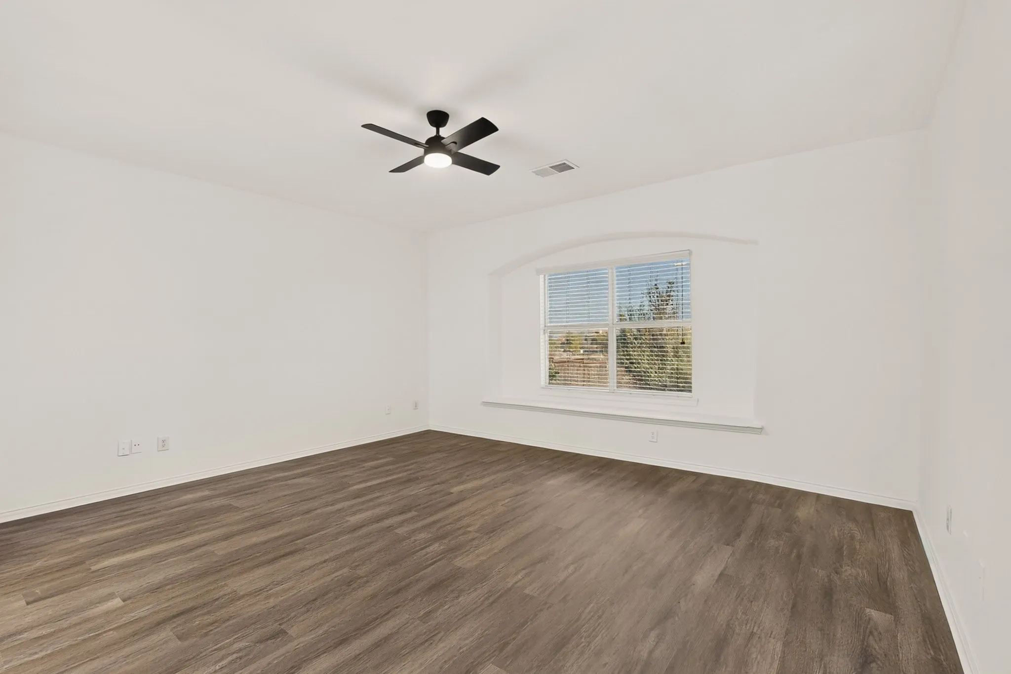 Wood-finish flooring, white walls, and a window with an arched architectural detail