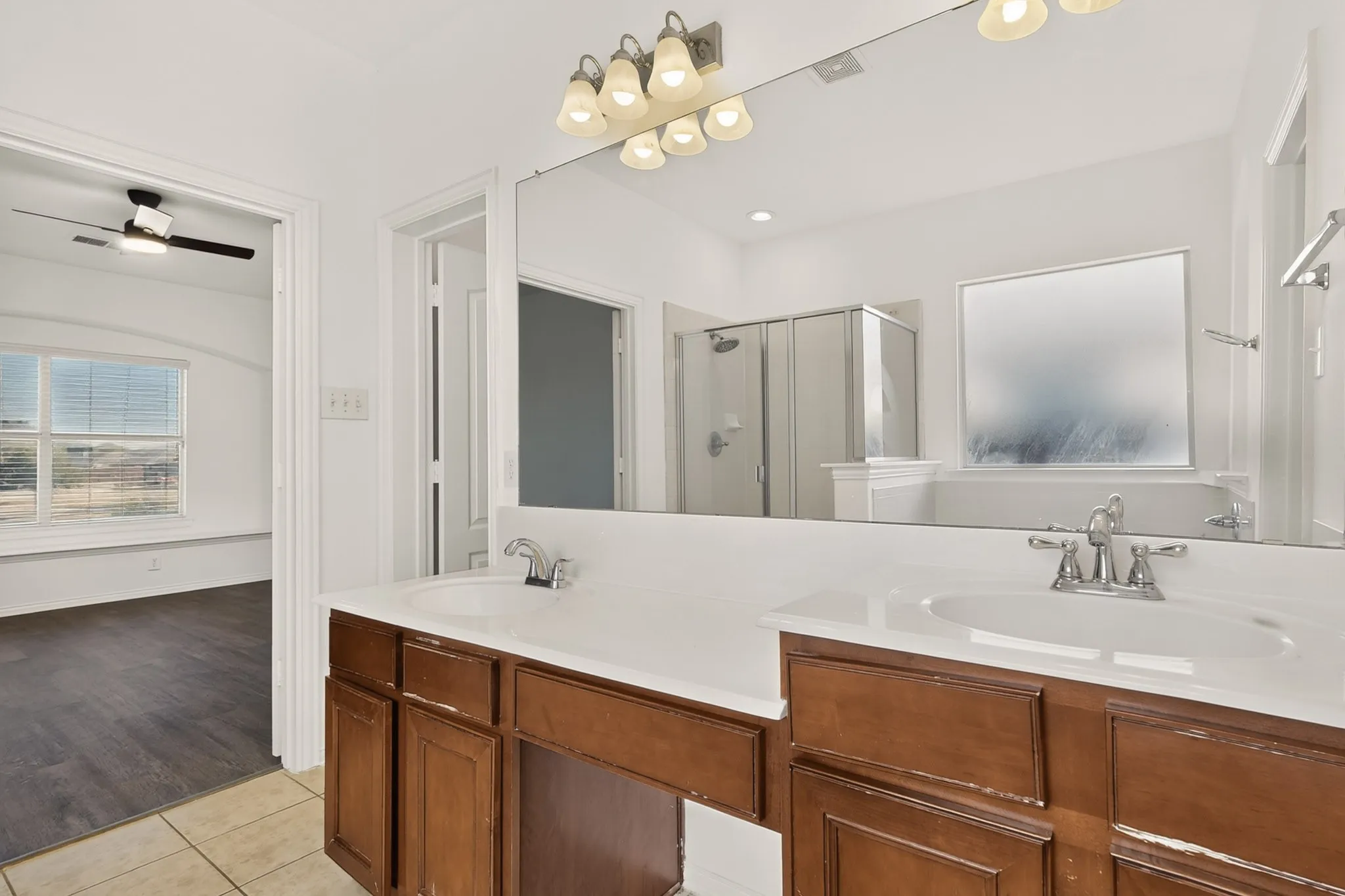 Dual vanity with integrated sinks, wood-finish cabinetry, and chrome fixtures