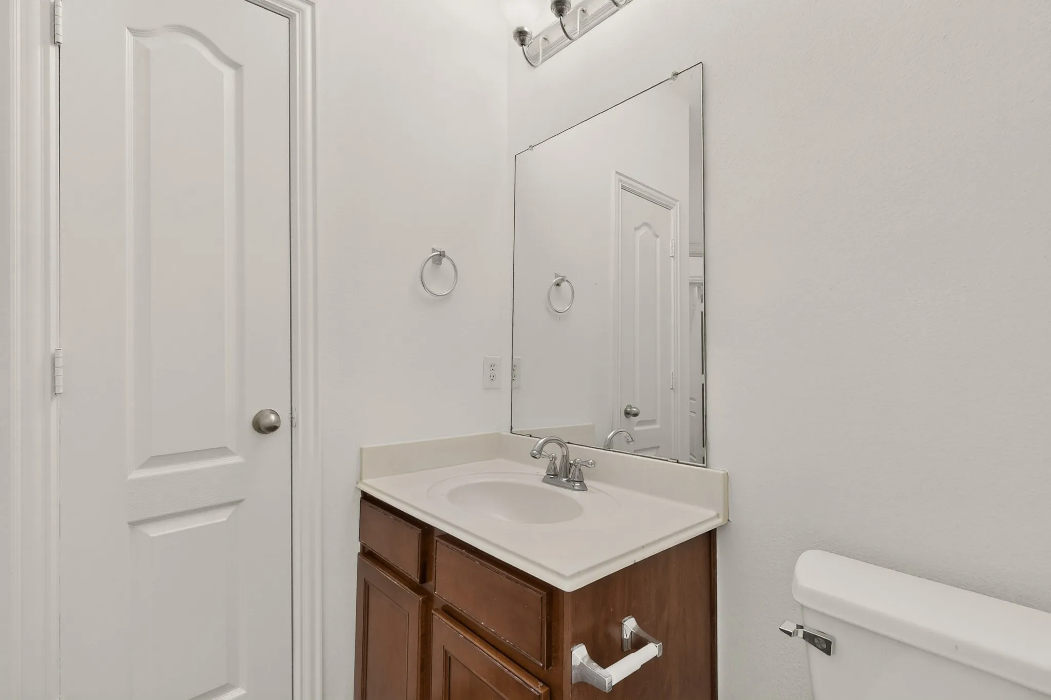 Bathroom vanity with integrated sink, wood-finish cabinetry, and a large wall-mounted mirror
